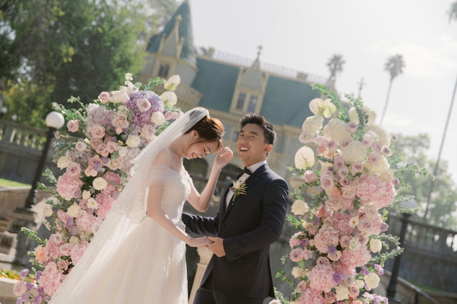 Wedding celebration with pink floral decorations against castle backdrop.