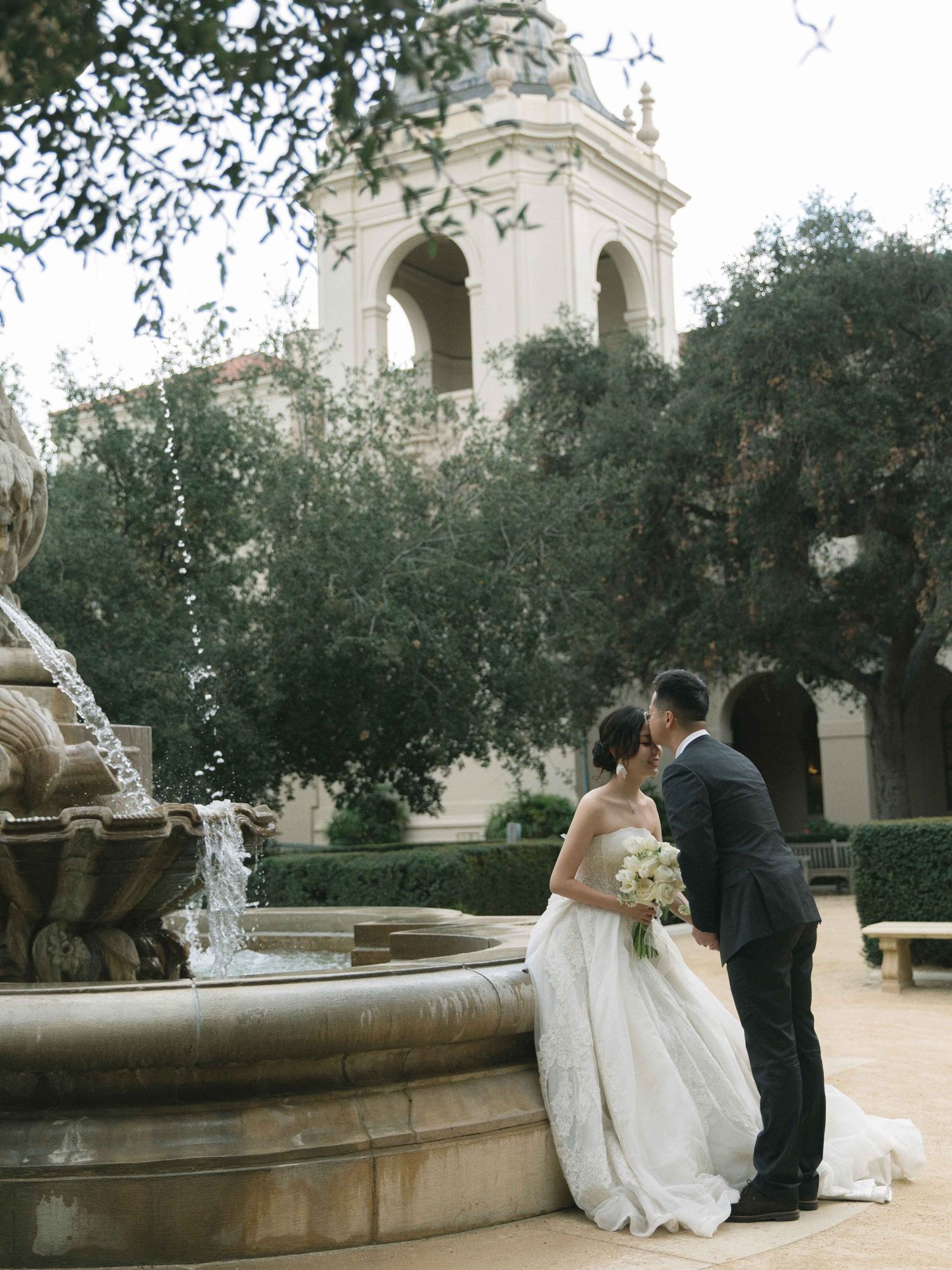 Newlyweds sharing romantic moment near fountain at elegant venue.