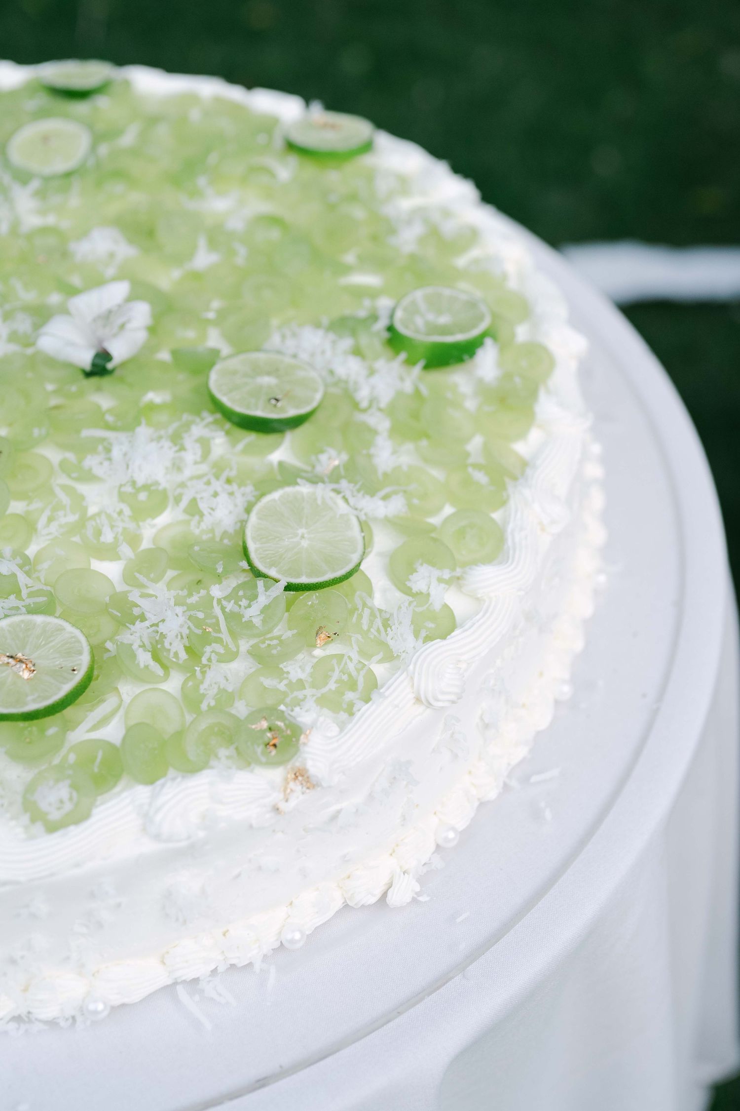 White frosted cake decorated with fresh lime slices and coconut flakes.