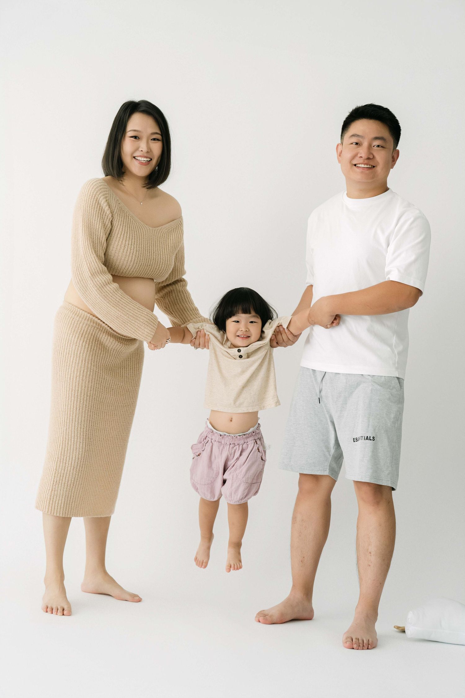 Family maternity photo session showing playful moments against white backdrop.