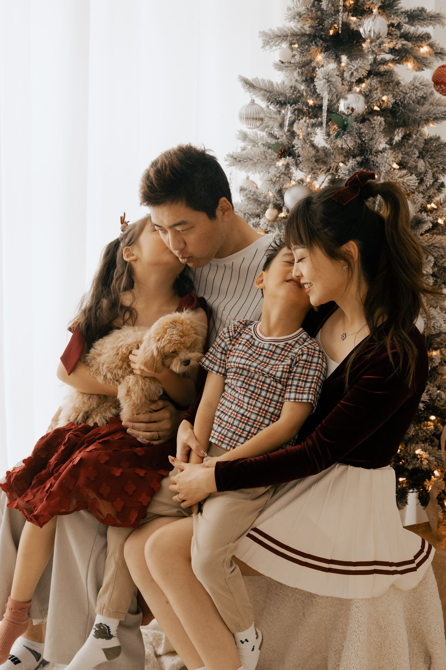 Intimate family portraits taken in front of a decorated Christmas tree.