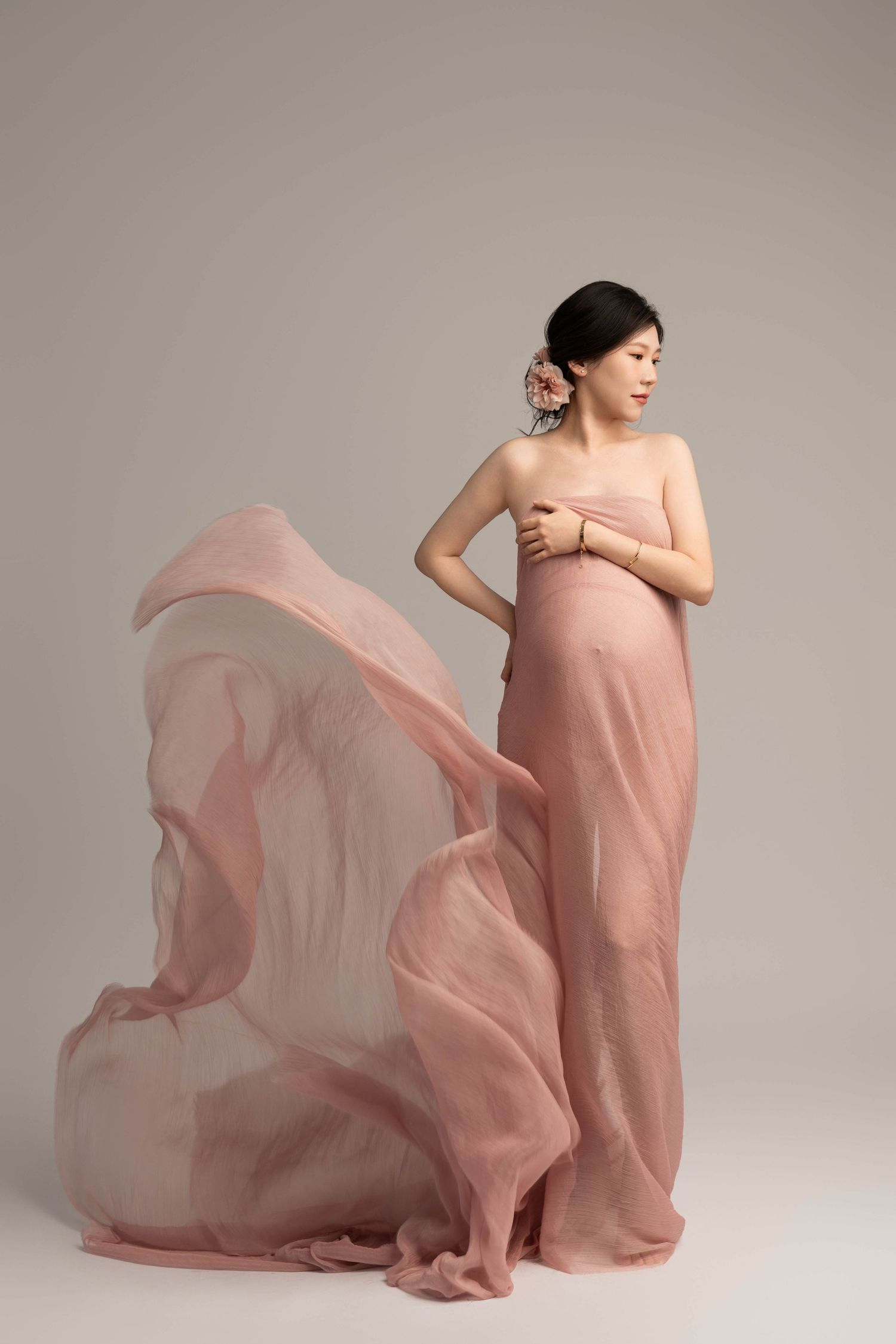 Artistic maternity photos with flowing pink fabric creating ethereal movement.