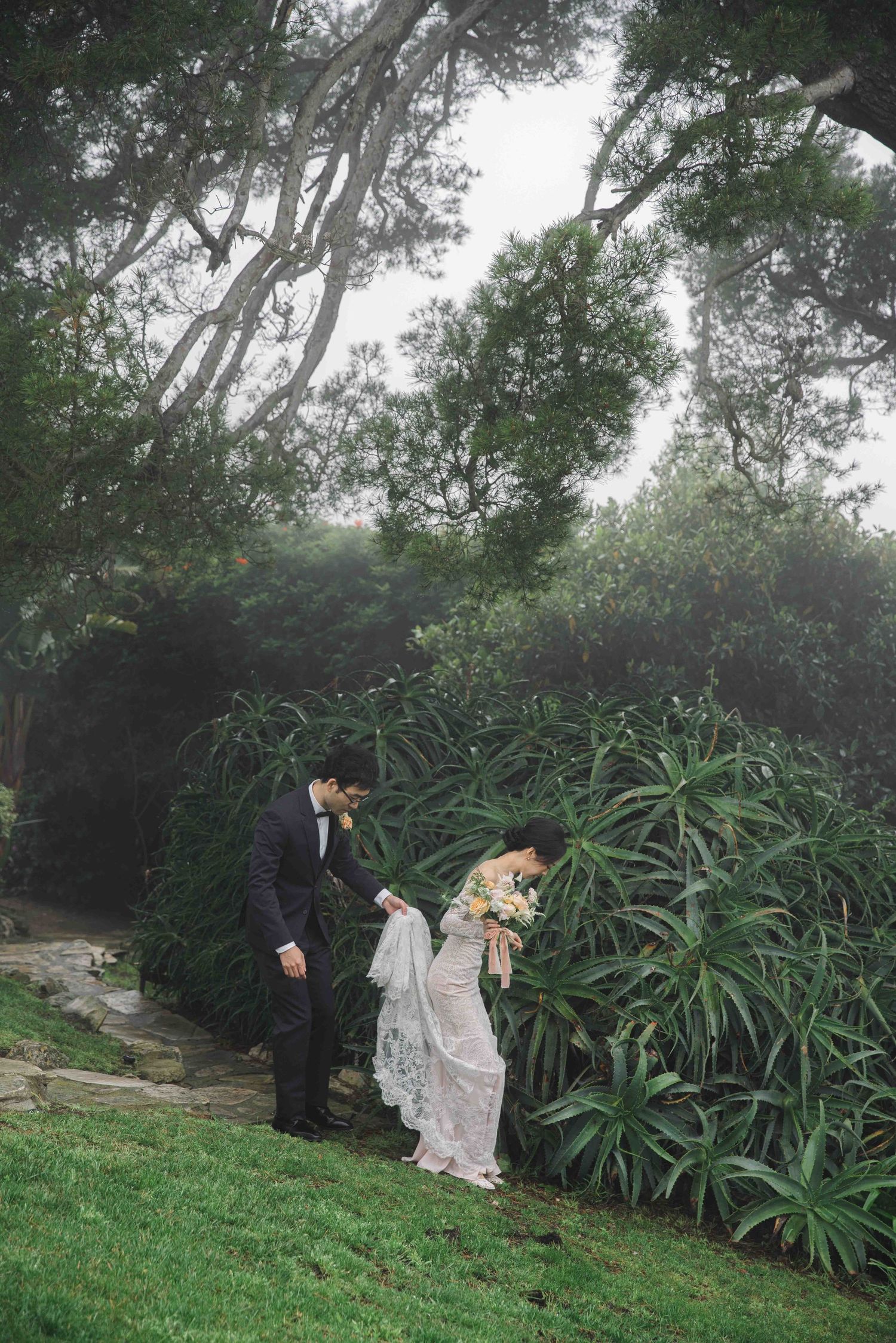 Romantic wedding photos in a misty garden setting with lush green foliage backdrop.