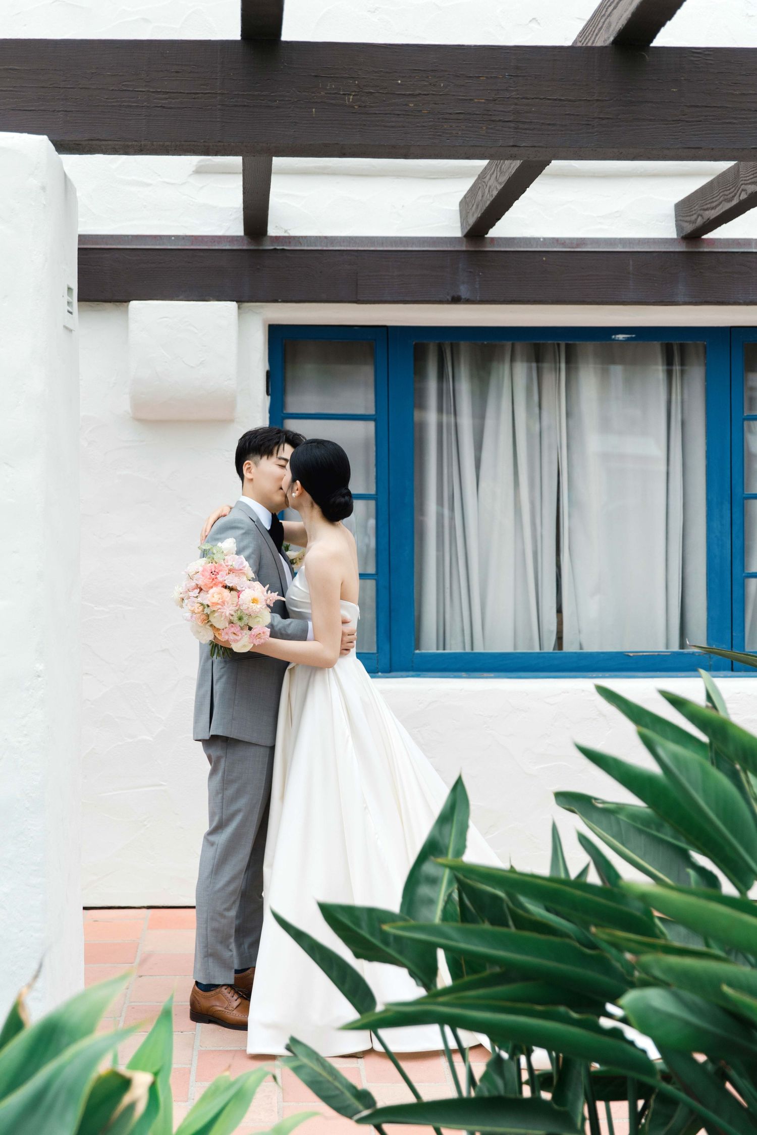 Wedding couple sharing intimate moment against white wall with blue accents.