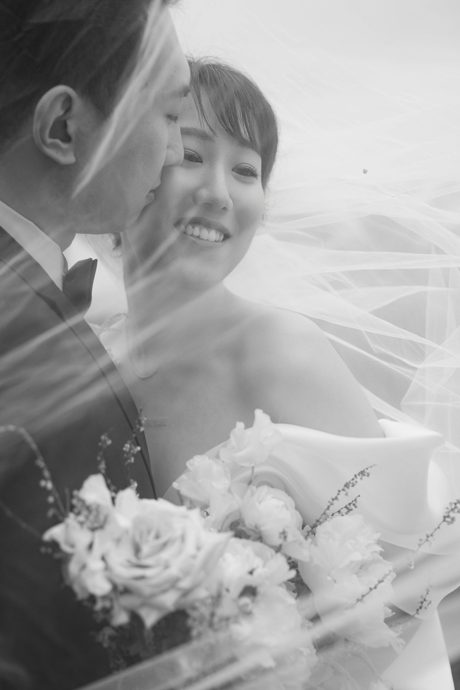Black and white close-up portrait through wedding veil with soft focus.