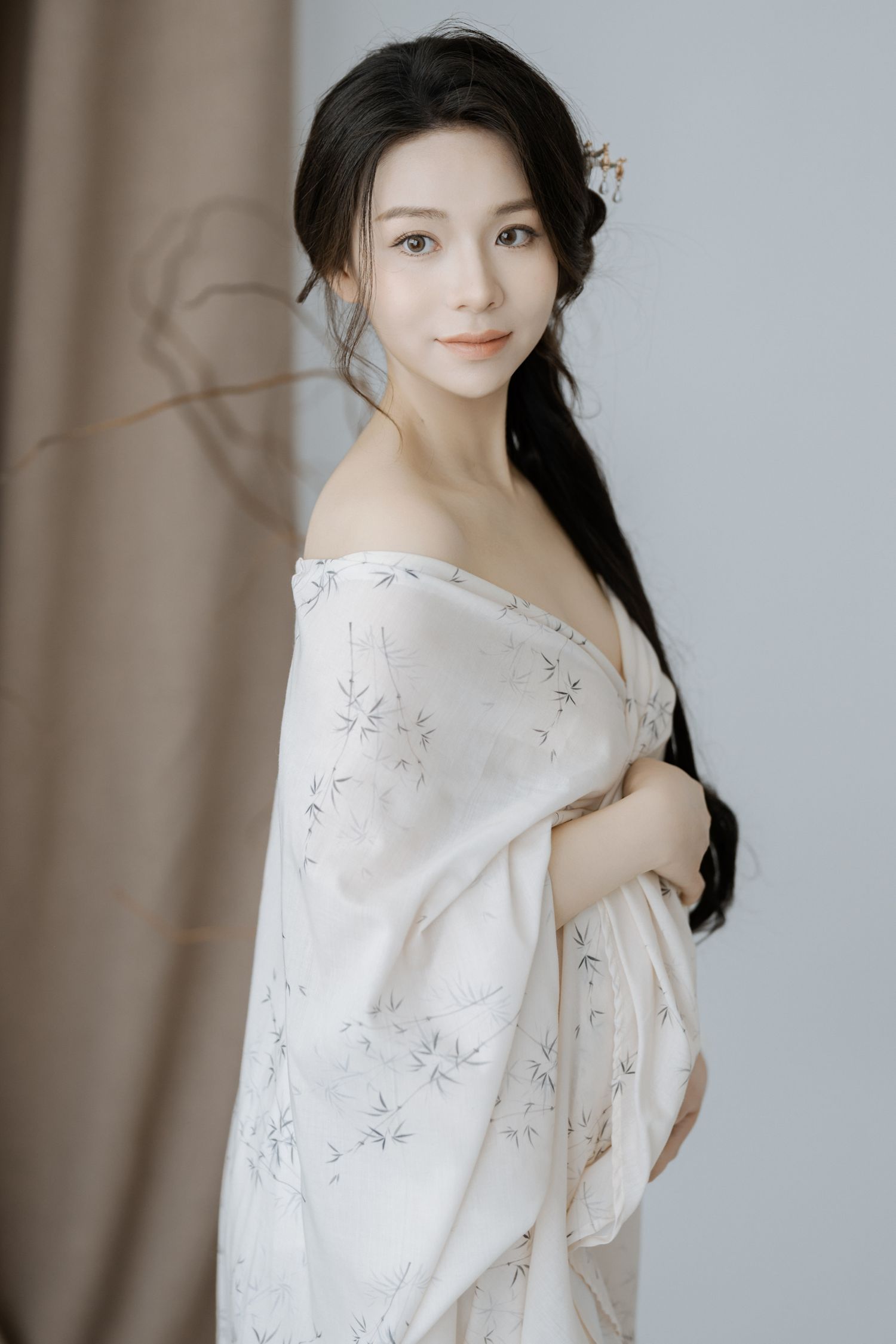Elegant portrait in floral off-shoulder dress against neutral background.