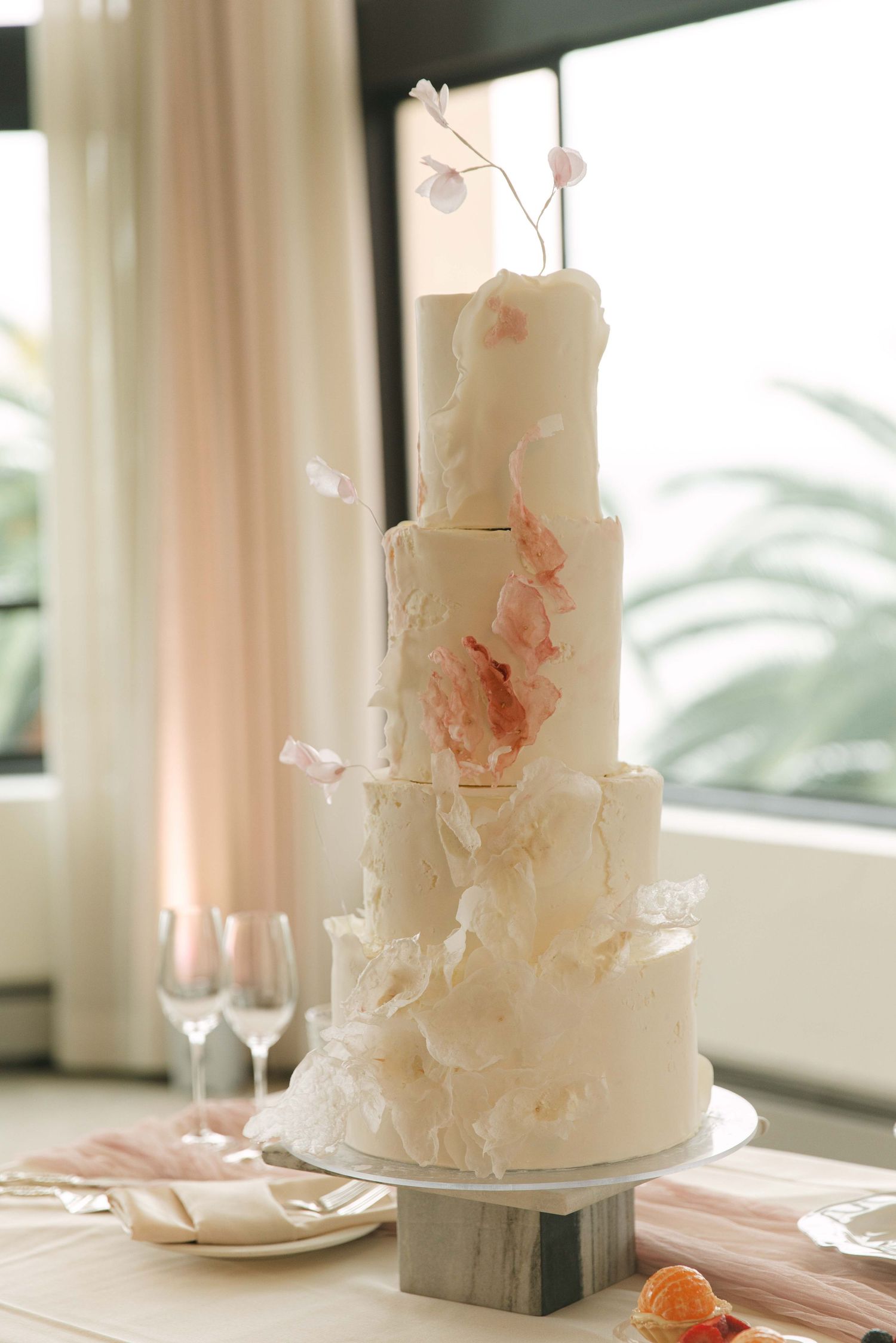 Elegant white wedding cake with delicate floral details and blush accents.