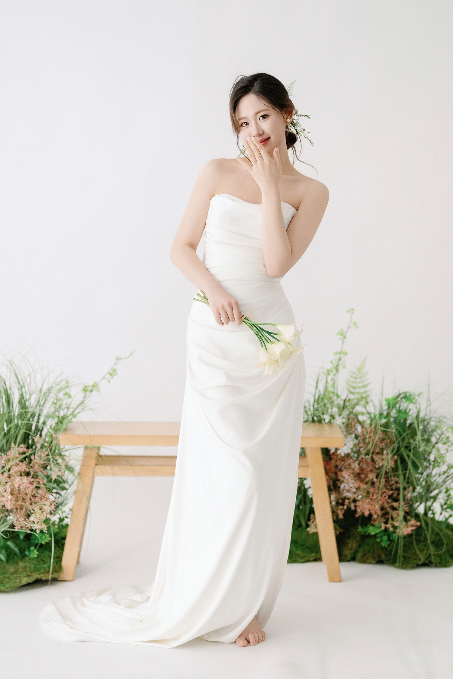 Ethereal bridal portraits with natural garden elements and wooden furniture in studio setting.
