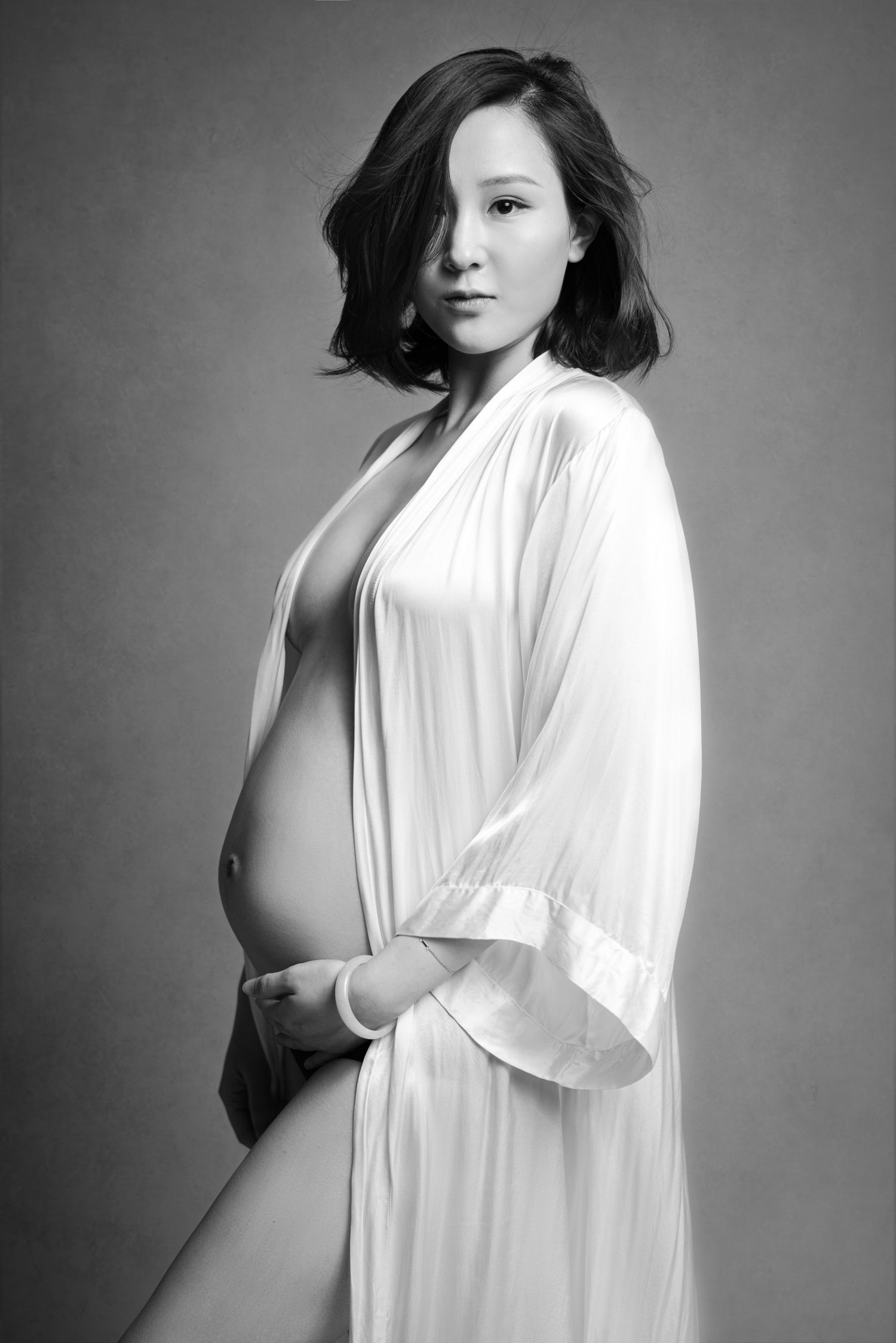 Black and white studio maternity portraits featuring white flowing garments.