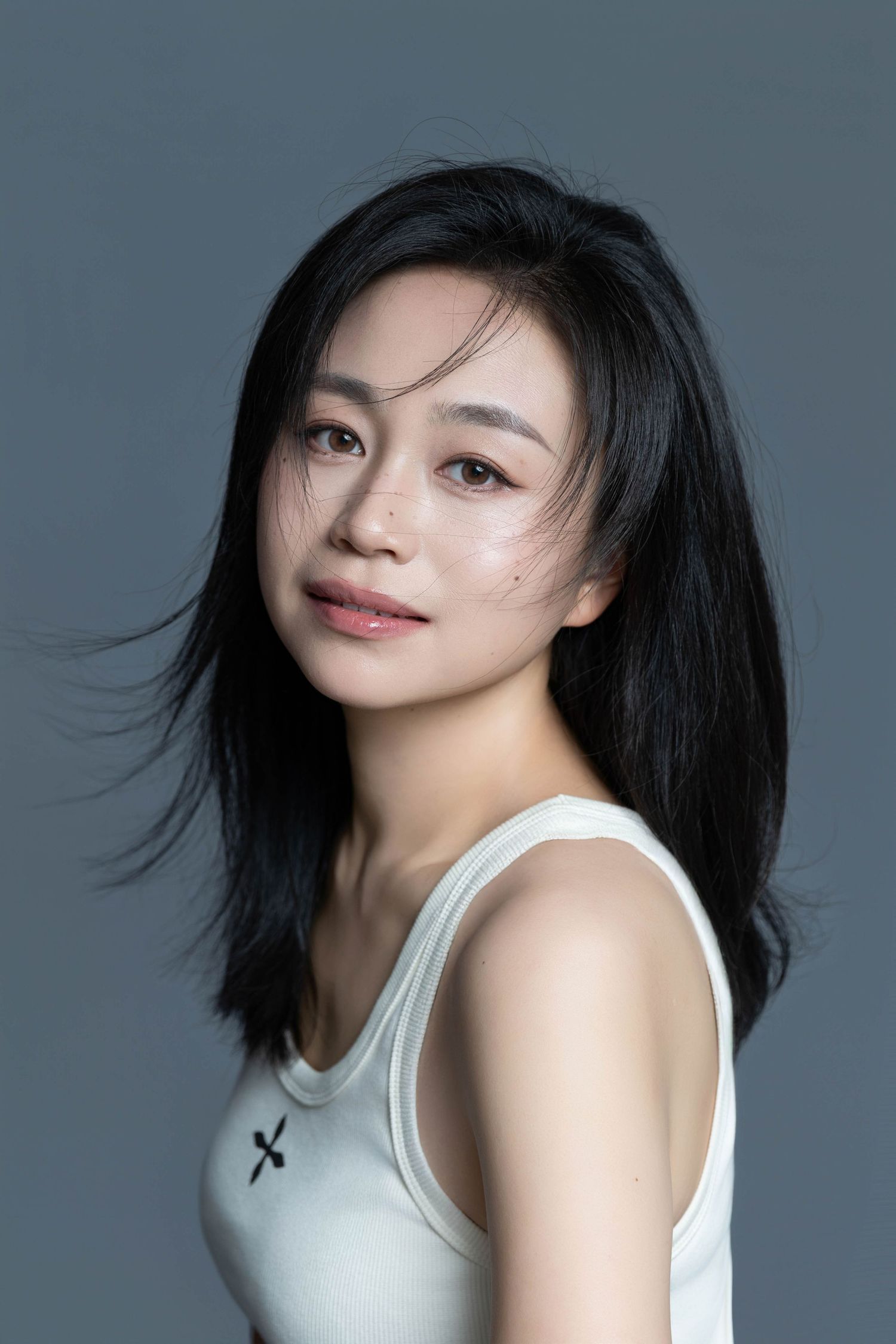 Modern portrait with wind-swept hair and minimalist white top.