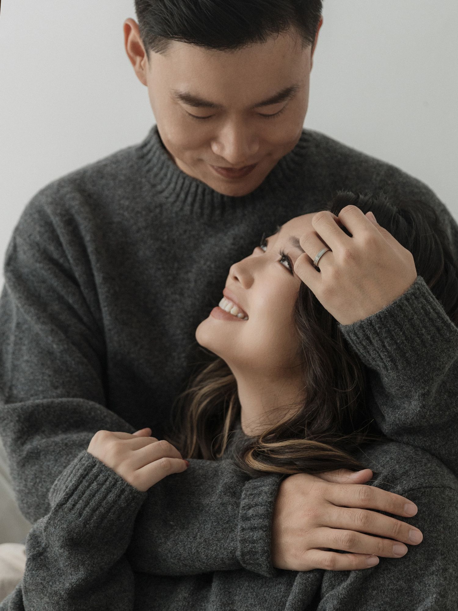 Intimate couple portrait with both wearing matching gray sweaters.