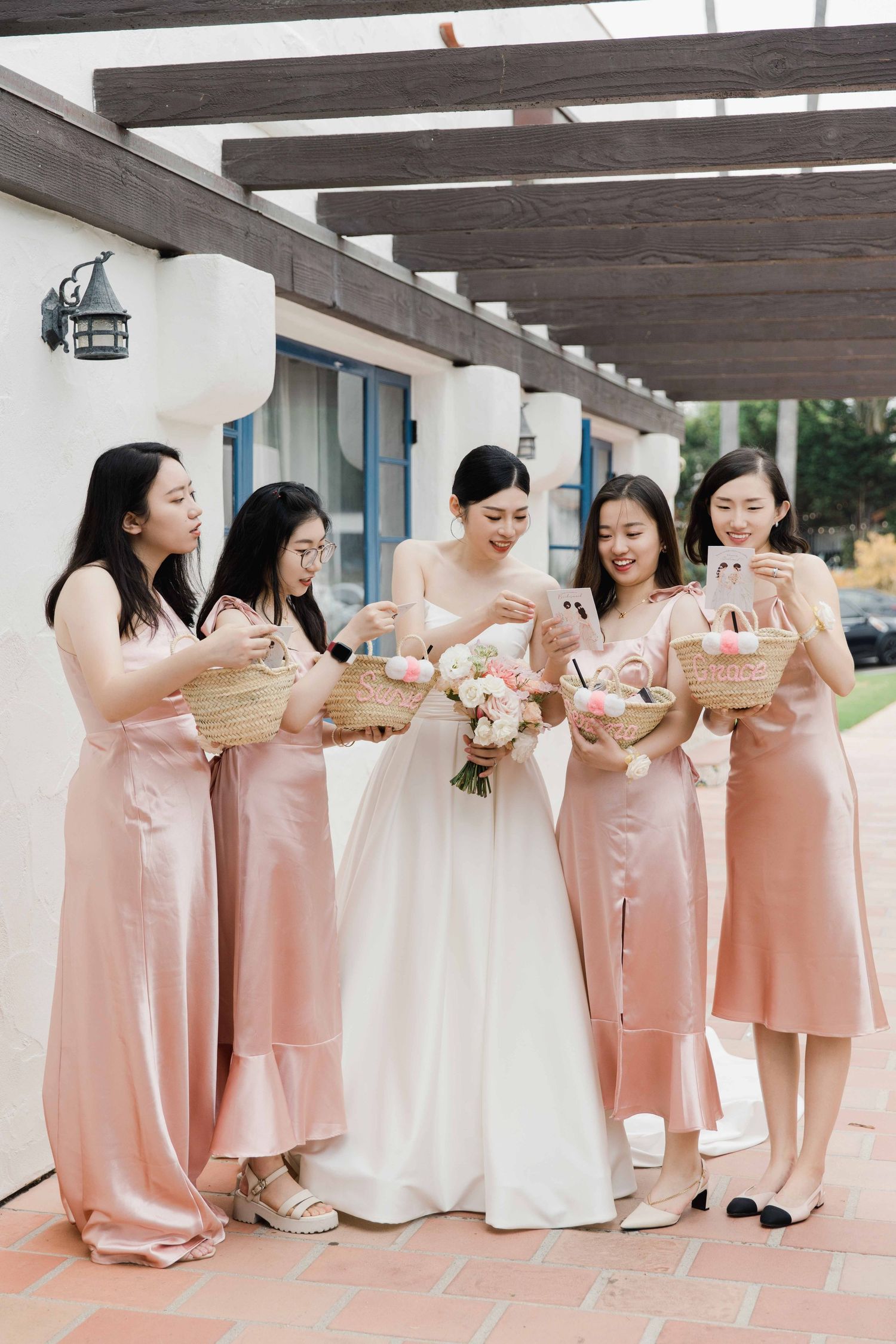 Bridesmaids in pink dresses gather together during outdoor wedding celebration.