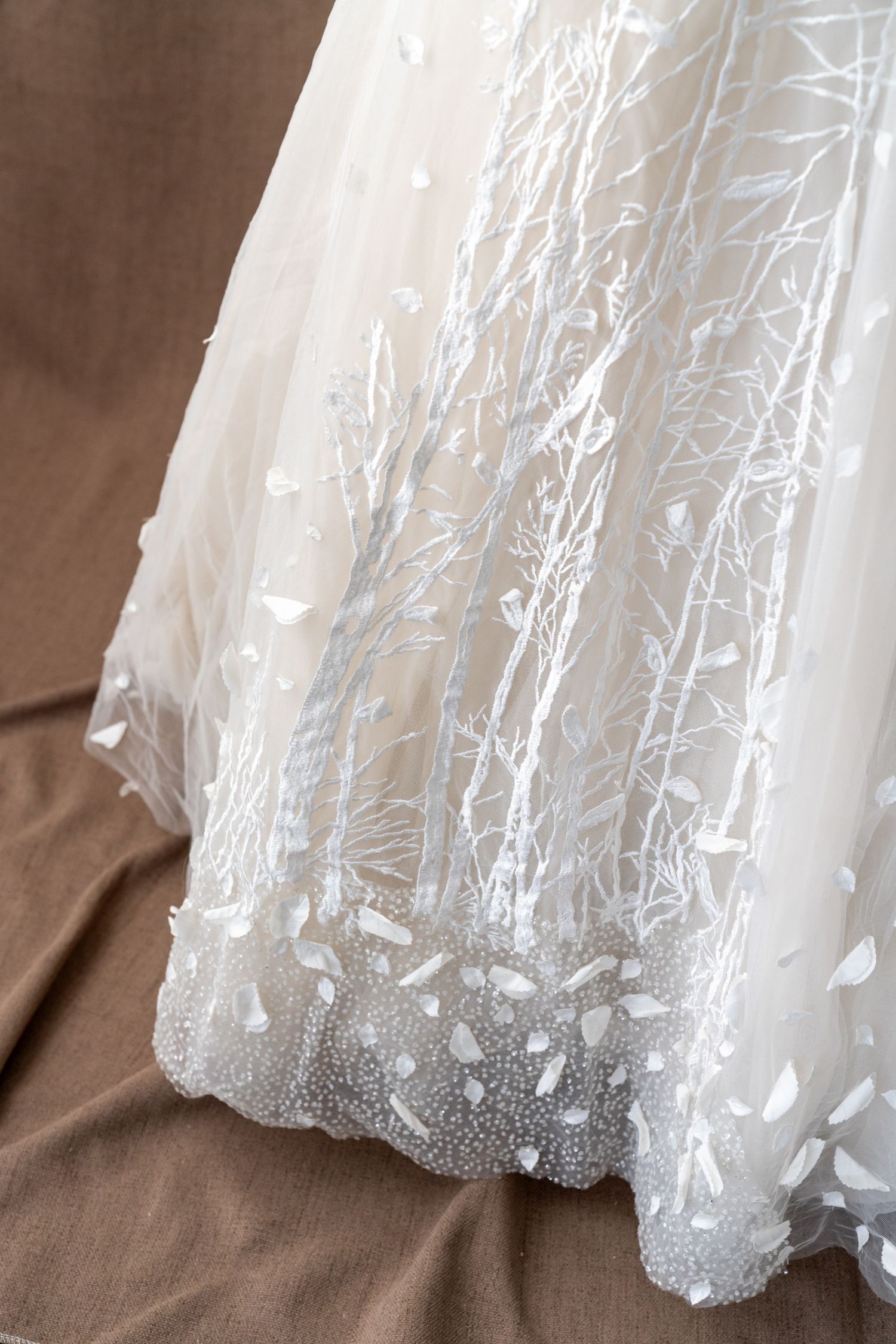 Detailed view of wedding dress hem with delicate embroidered pattern and beading.