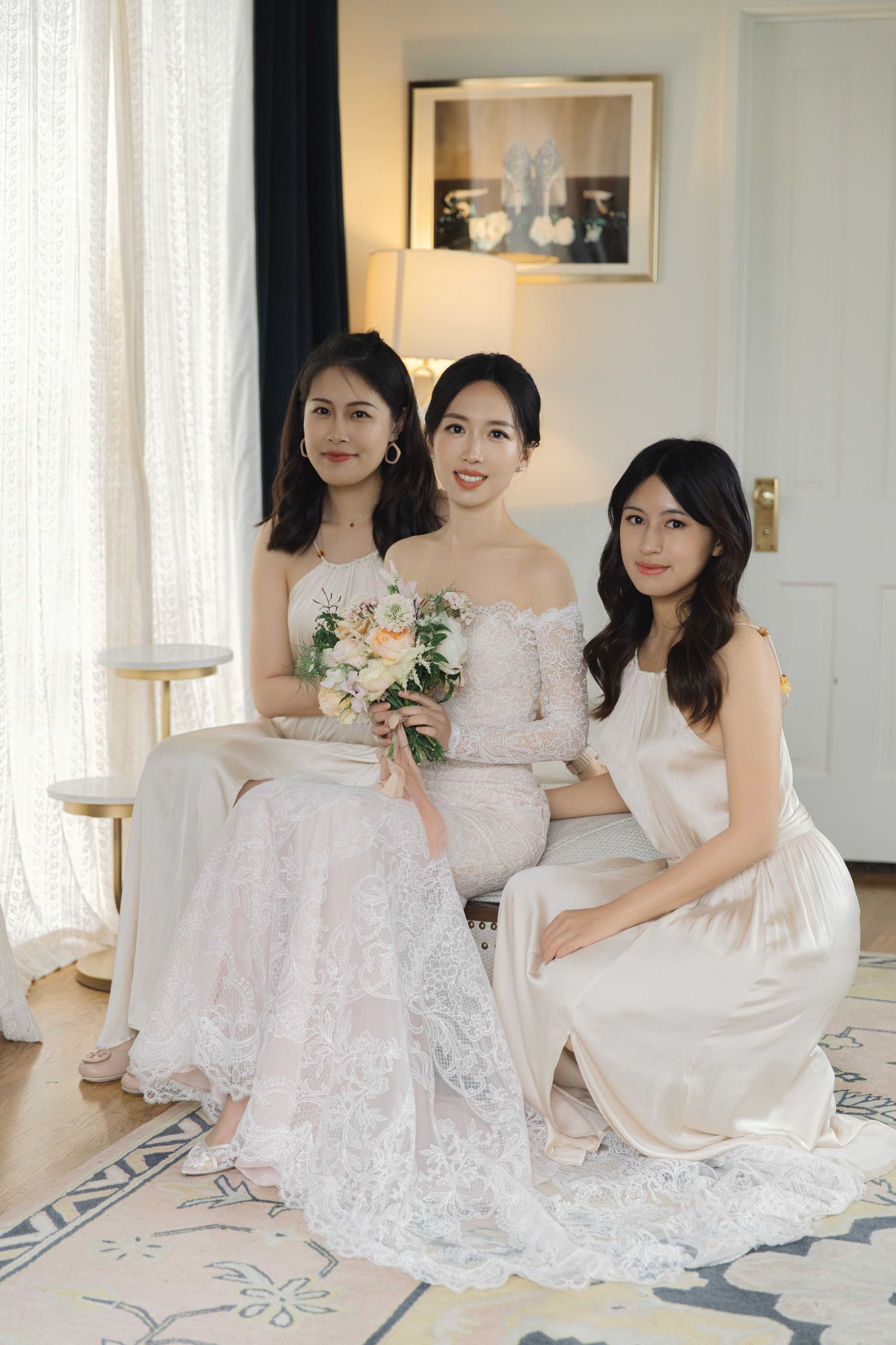 Bridesmaids in white dresses gather for intimate portraits in a bright, modern room.