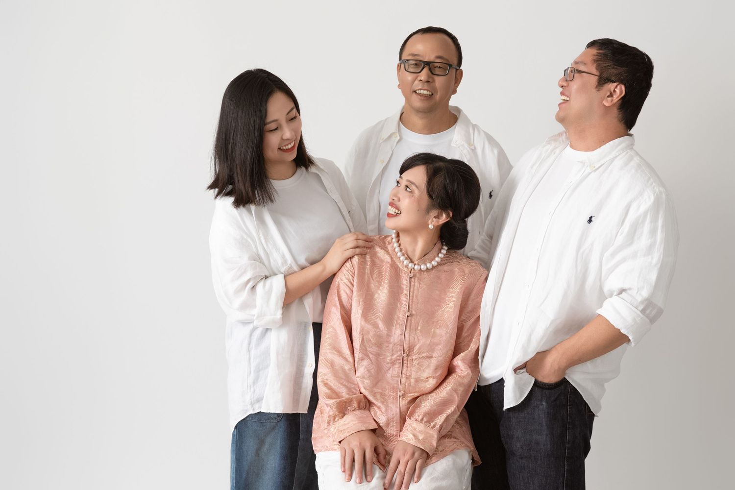 Family of four wearing coordinated outfits poses together against a white studio background.