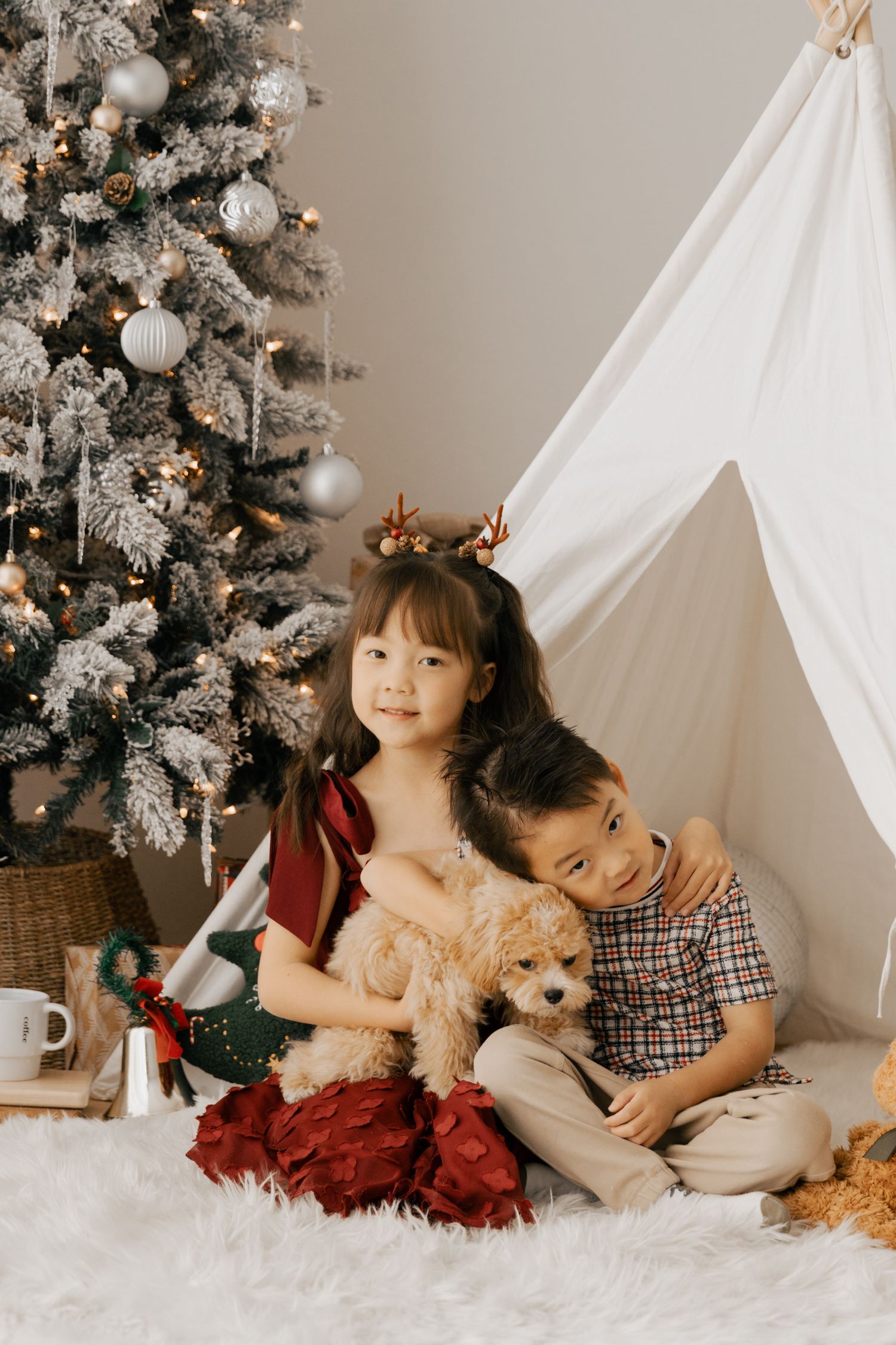 Family relaxing by a Christmas tree with stuffed animals and holiday decorations.