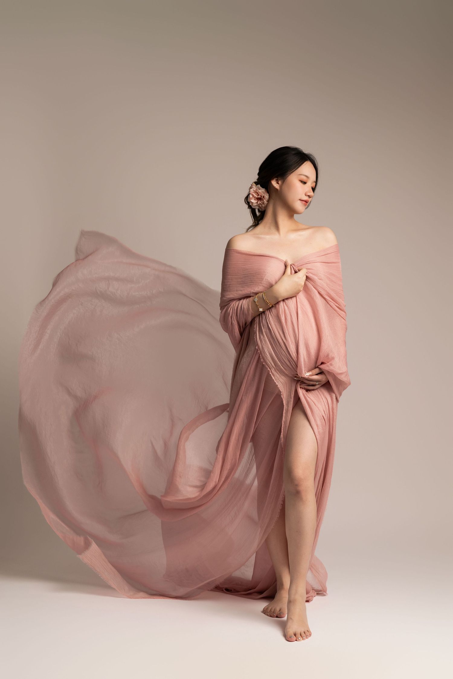 Ethereal maternity session with flowing pink fabric and artistic poses.