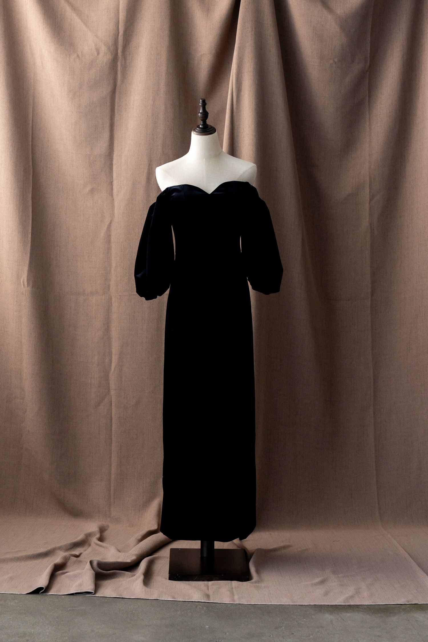 Multiple views of a black formal dress displayed on a mannequin against a brown backdrop.