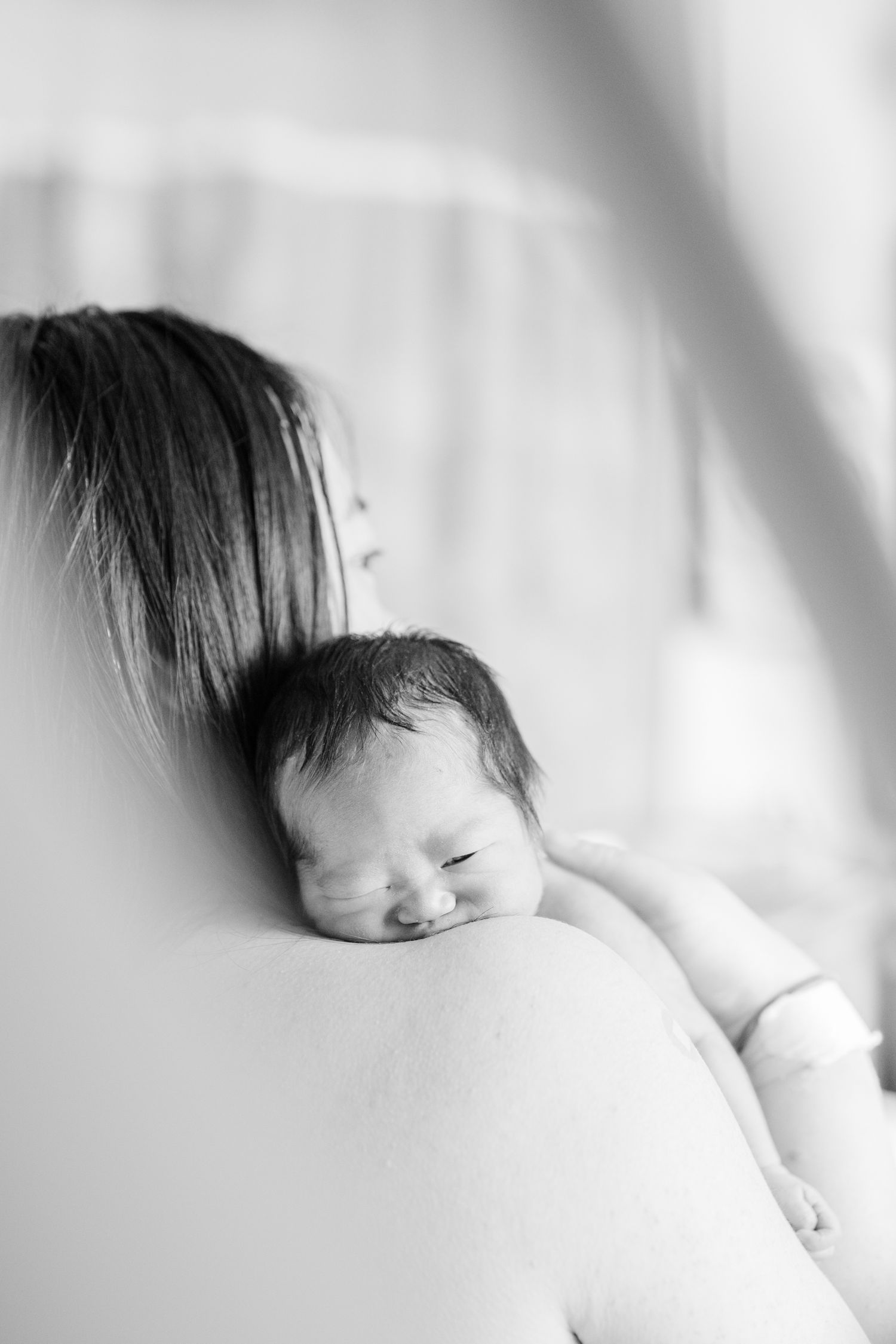 Peaceful black and white portrait of sleeping newborn on white bedding.