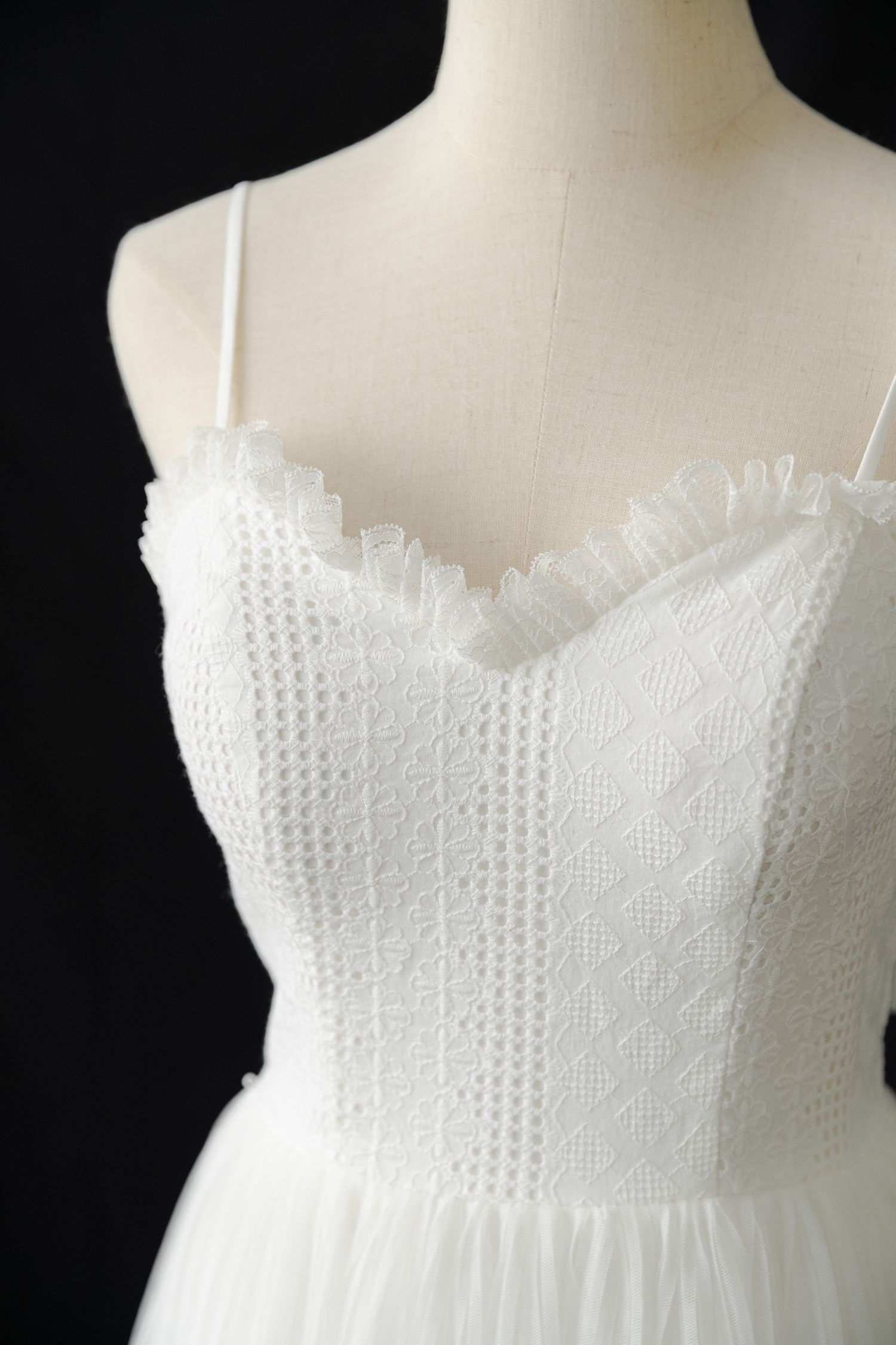 Detailed view of white textured bodice with spaghetti straps and sweetheart neckline.