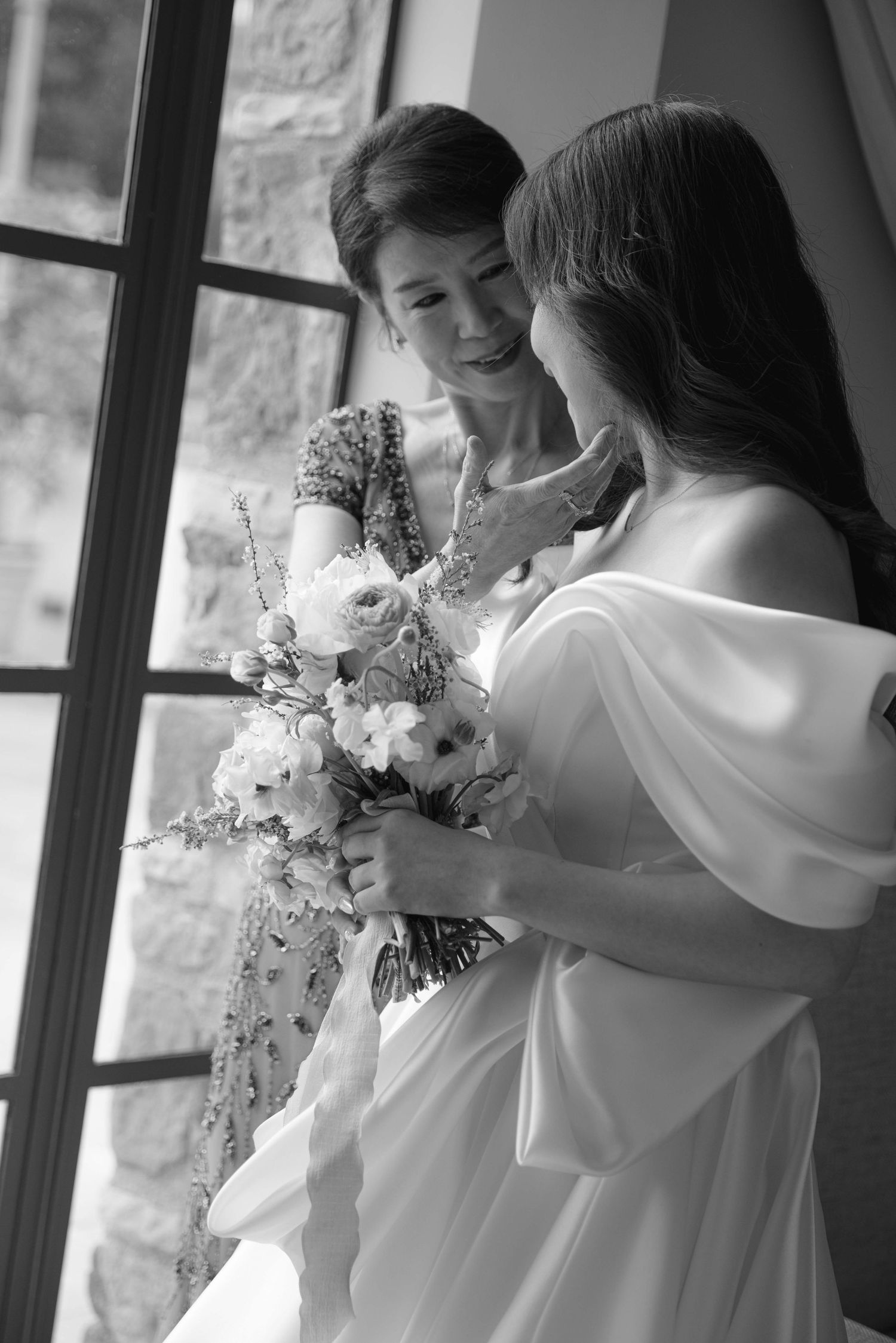 Black and white photos of people holding and admiring wedding bouquets by a window.