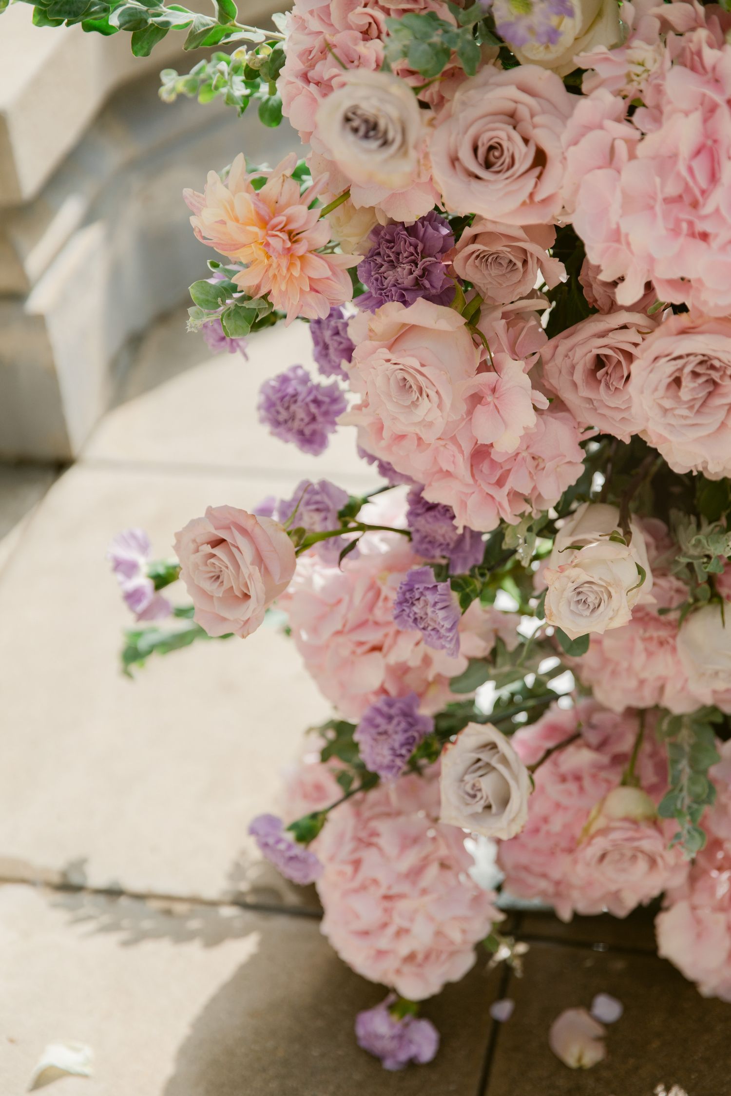 Delicate pink and purple floral arrangements with roses and lilacs create an elegant display.
