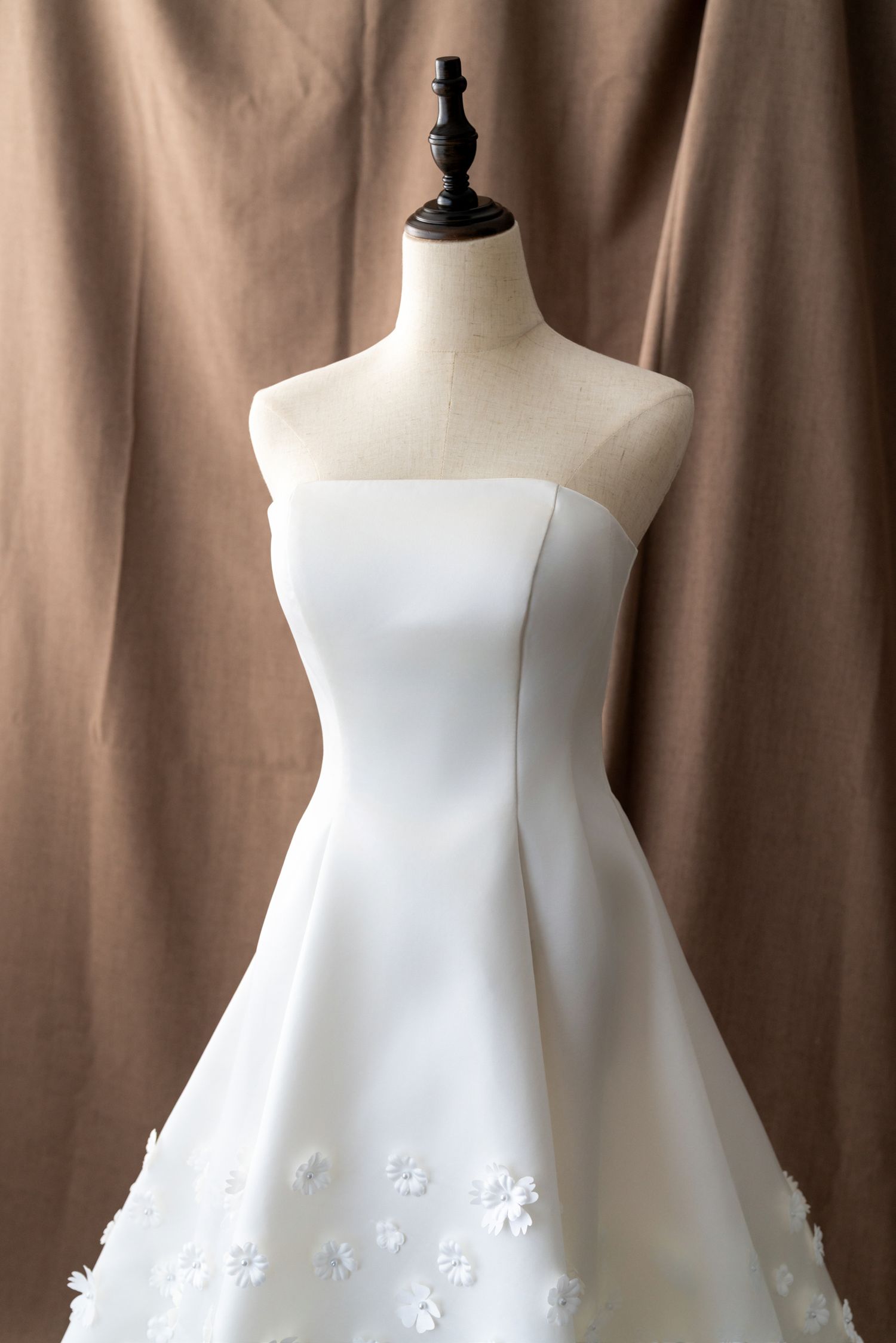 Modern white wedding gown with clean lines and delicate floral appliques at hem.