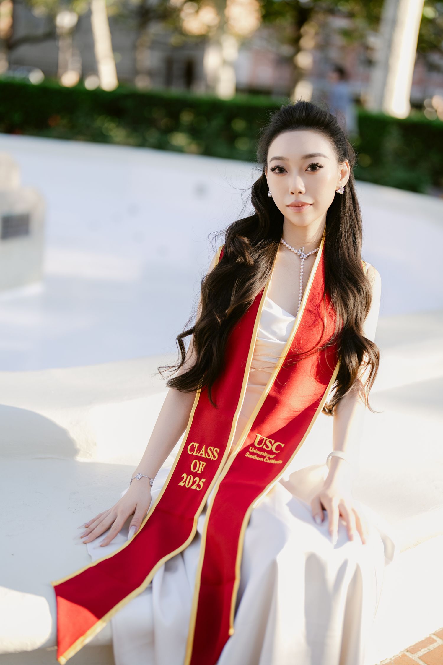 Graduation photos at USC wearing red and gold stole against architectural backdrop.
