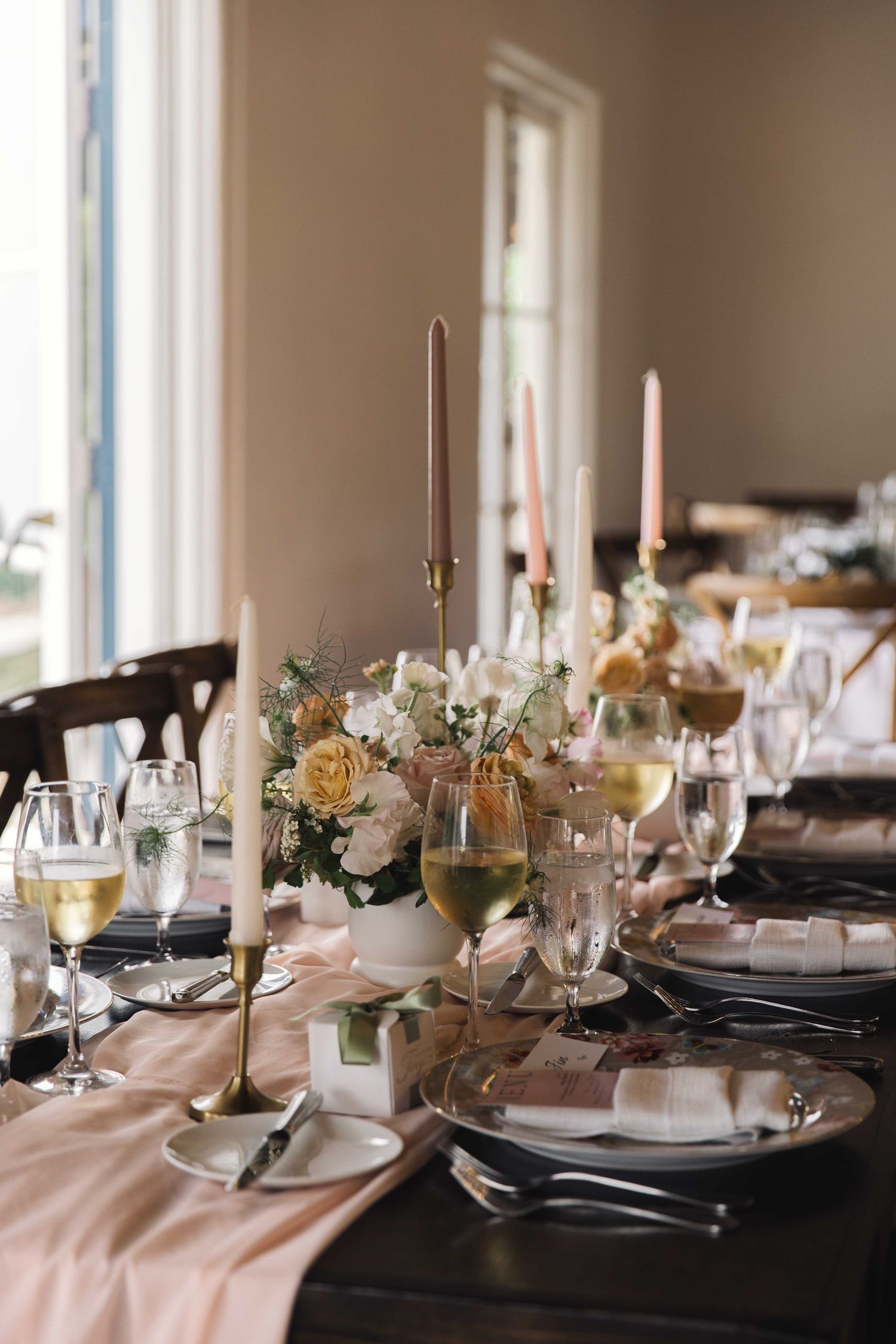 Elegant wedding table setting with pink linens, candles, and floral centerpieces.