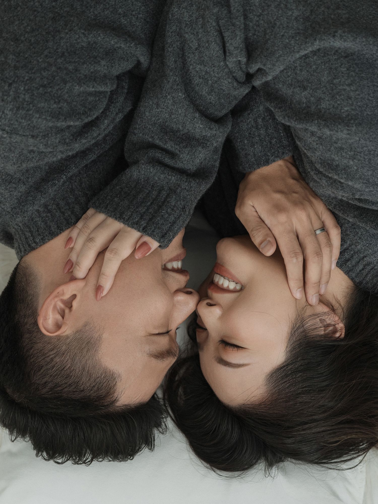 Close-up artistic portrait of a couple lying down and touching faces tenderly.