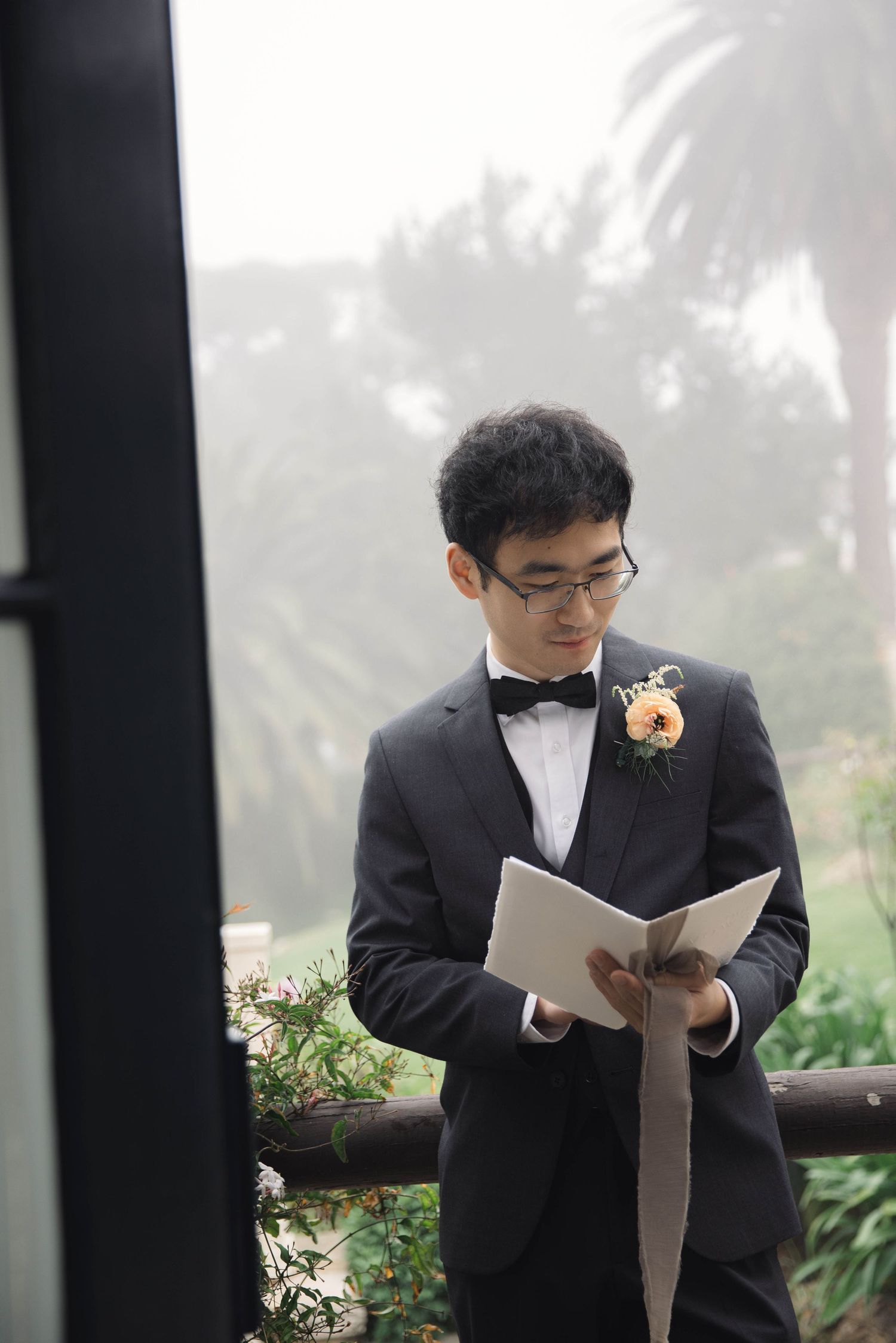 Person in formal attire reading from papers during an outdoor ceremony.