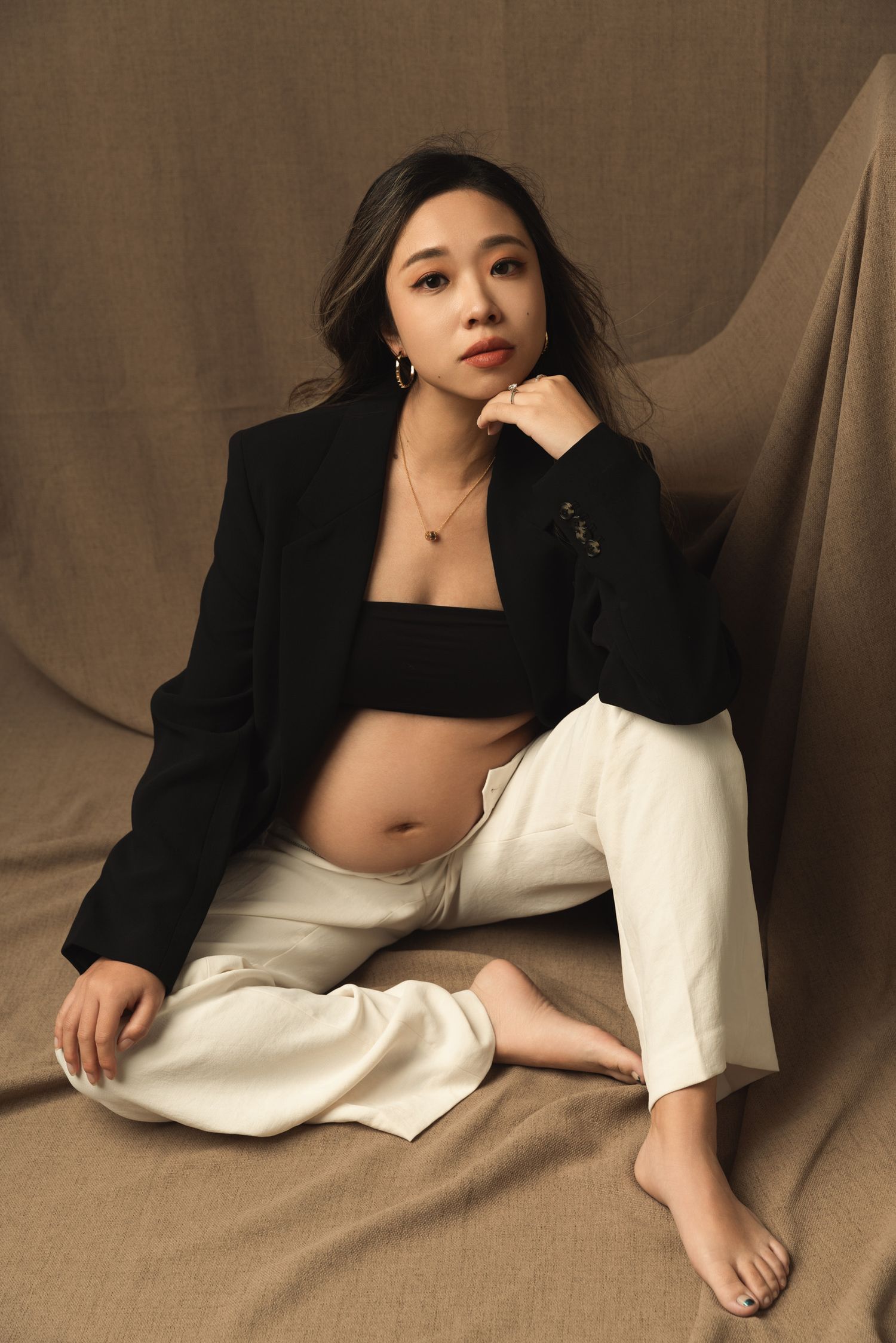 Artistic maternity portraits with relaxed poses on brown fabric backdrop.