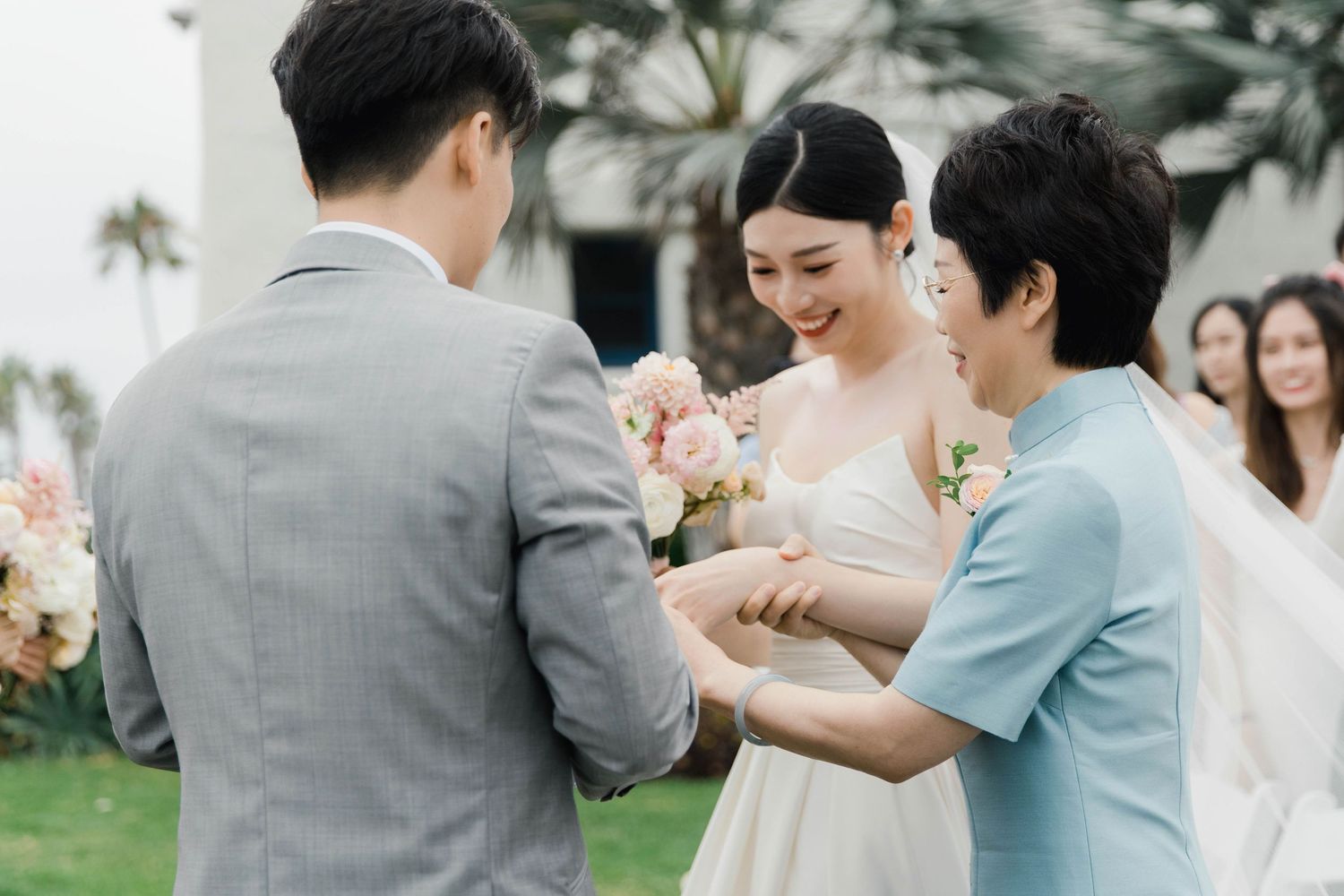 Wedding ceremony moment captured outdoors with floral arrangements and palm trees.