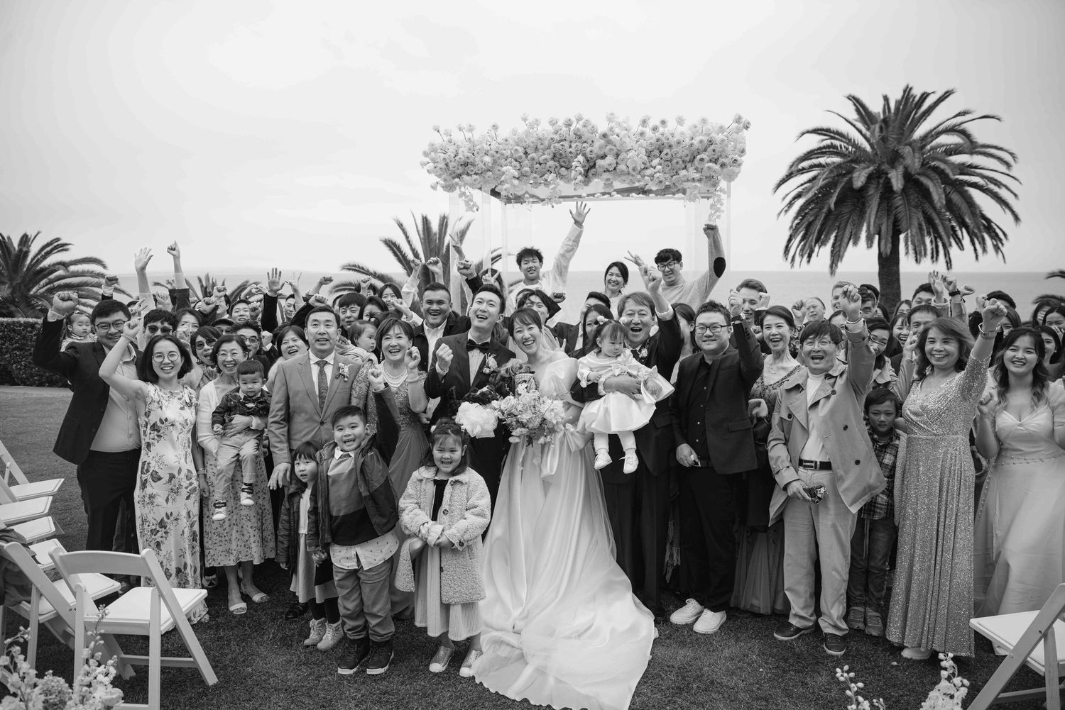 Large wedding party group photo with guests and wedding party on a sunny day.
