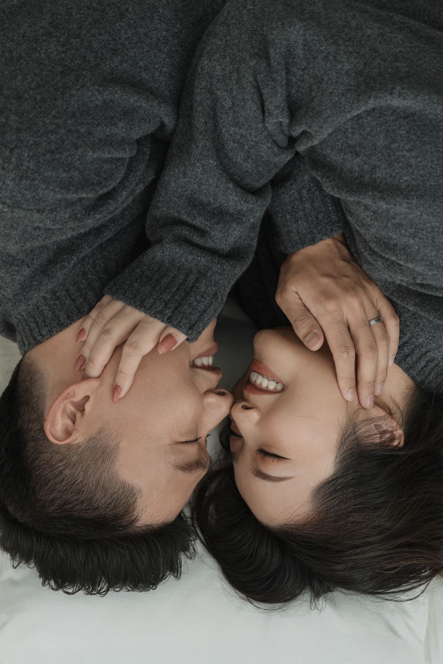 Intimate black and white portrait of couple lying close together.
