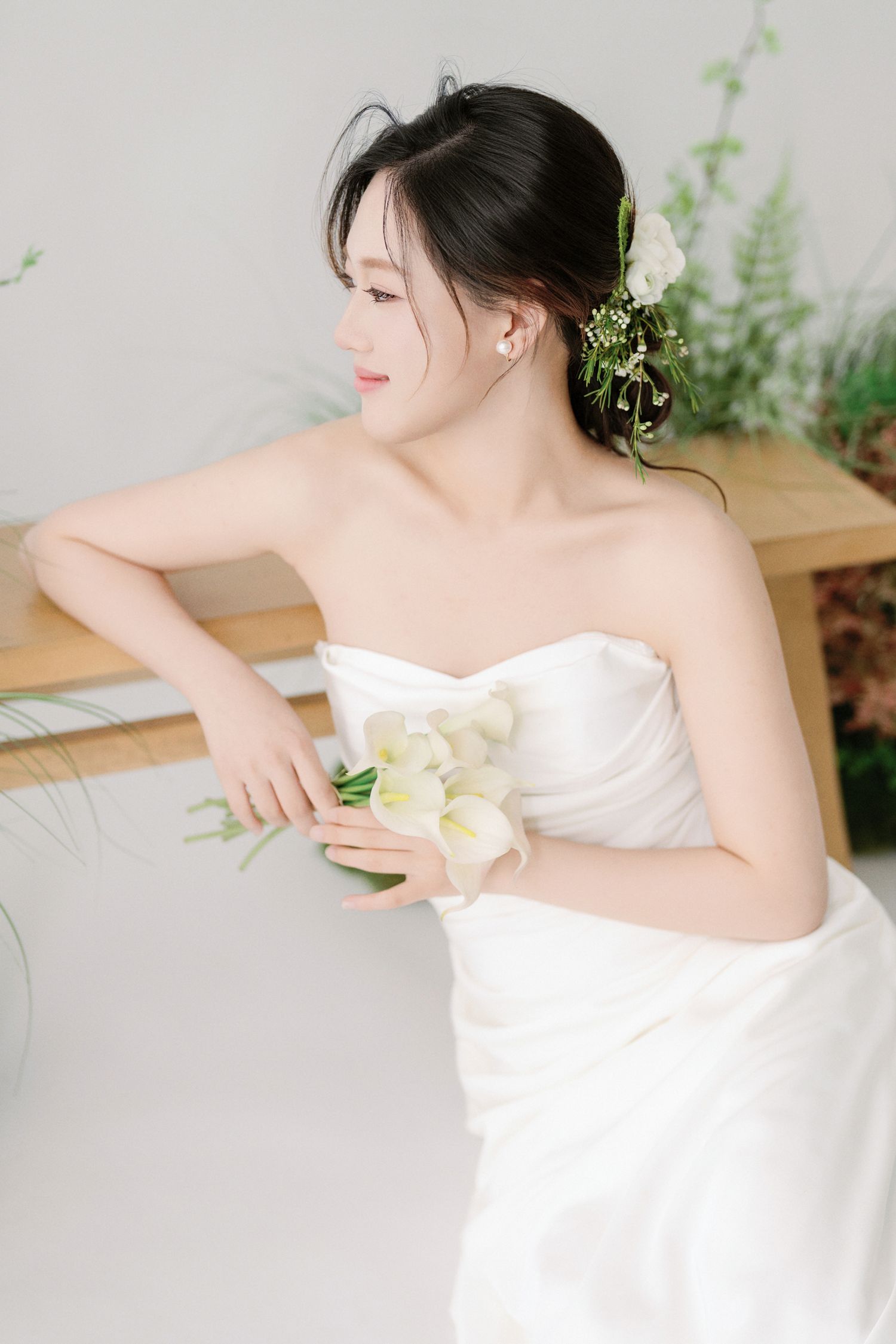 Artistic bridal portraits with flowing white gown and calla lily against minimalist setting.
