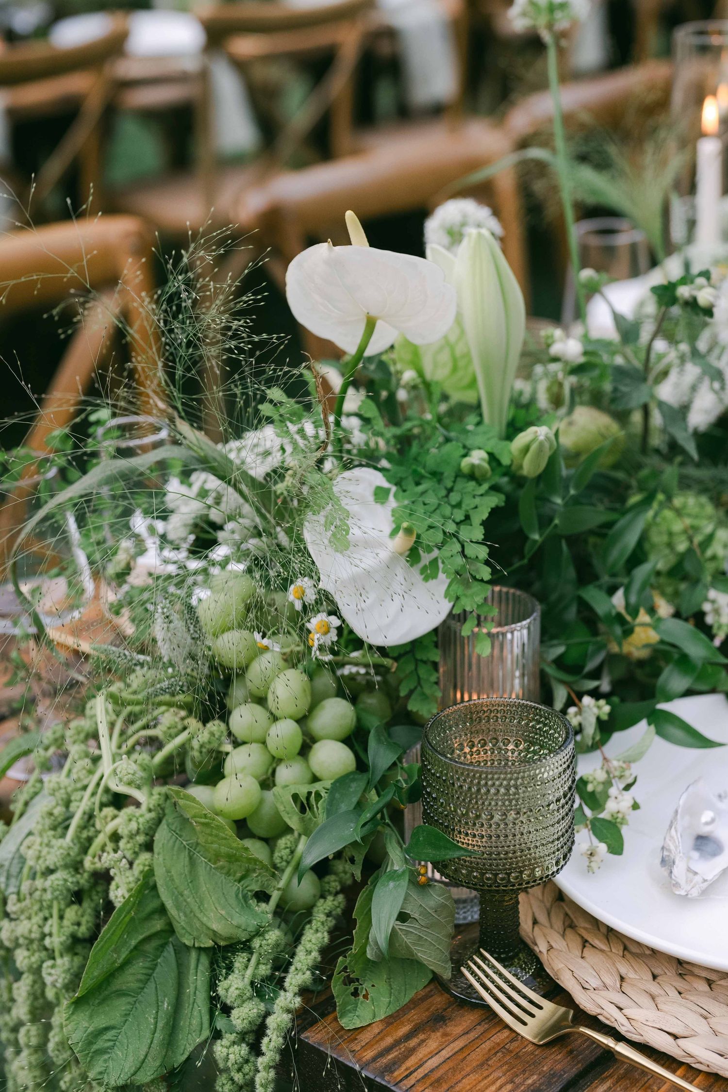 Organic table decor featuring fresh green fruit and delicate white flowers in glass vessels.