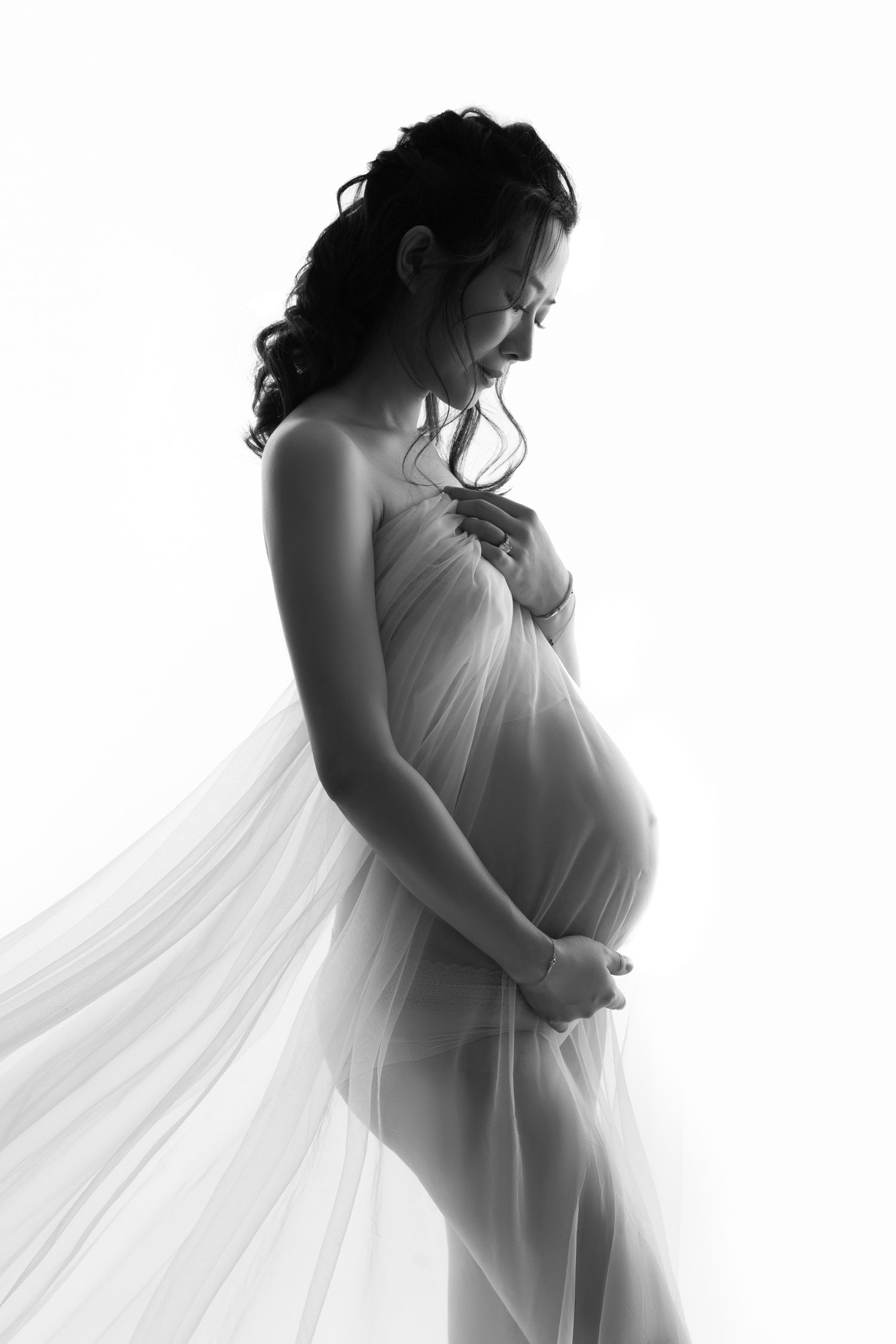 High-key maternity portraits with flowing white fabric creating ethereal silhouettes.