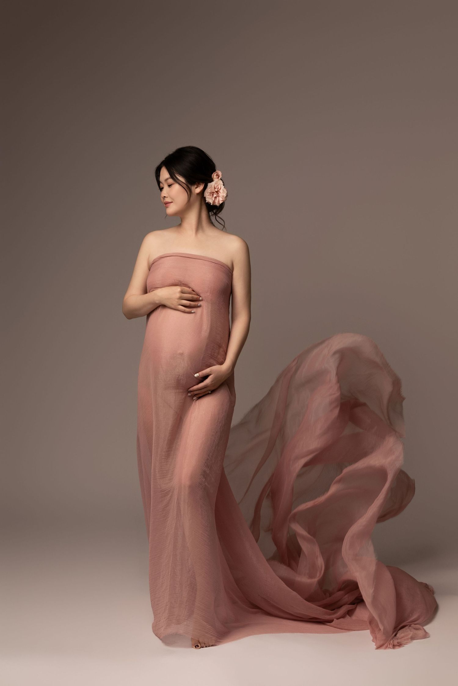Artistic maternity photos with flowing mauve fabric creating ethereal movement.