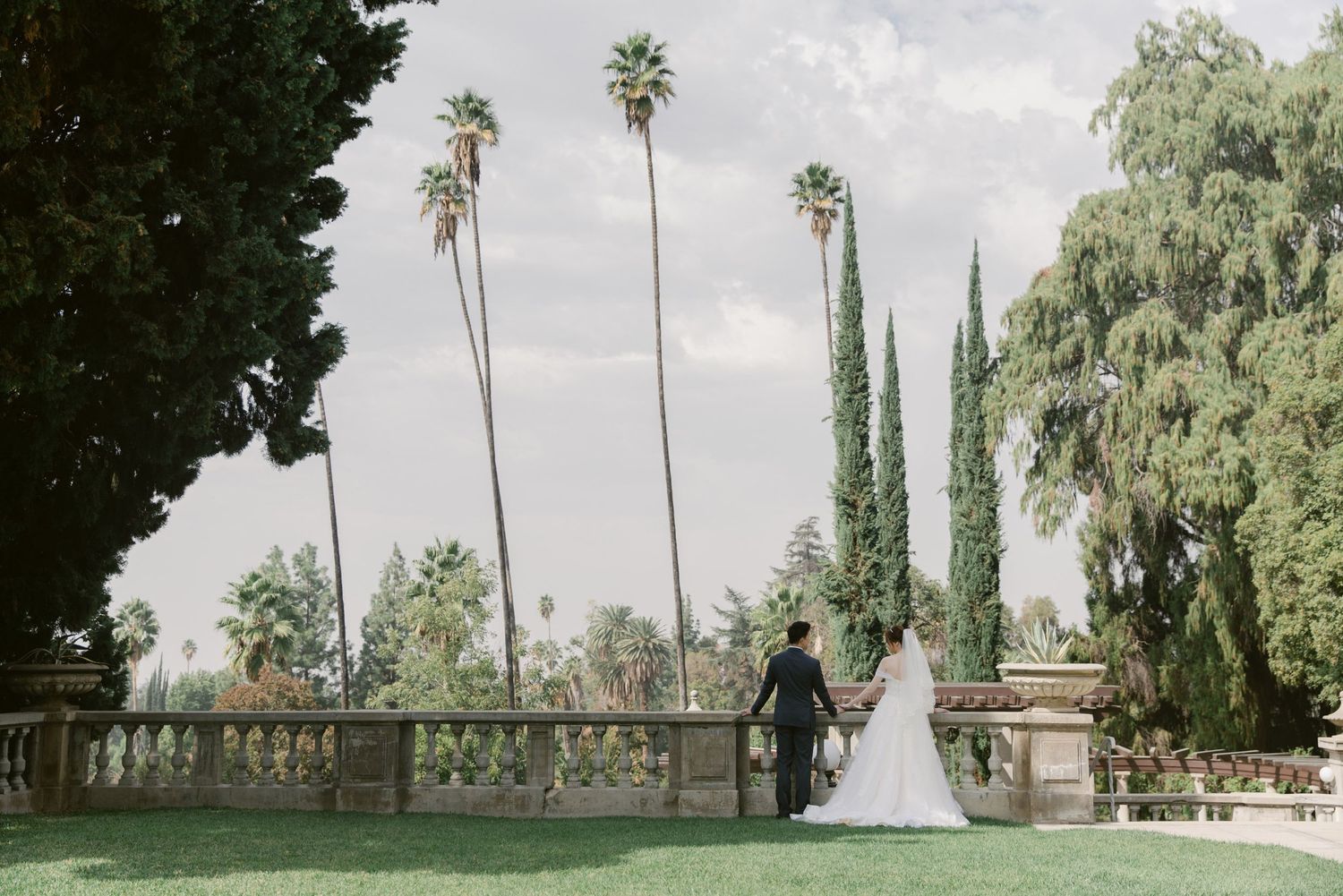 Scenic wedding portraits taken in a garden with tall cypress trees and natural landscape.
