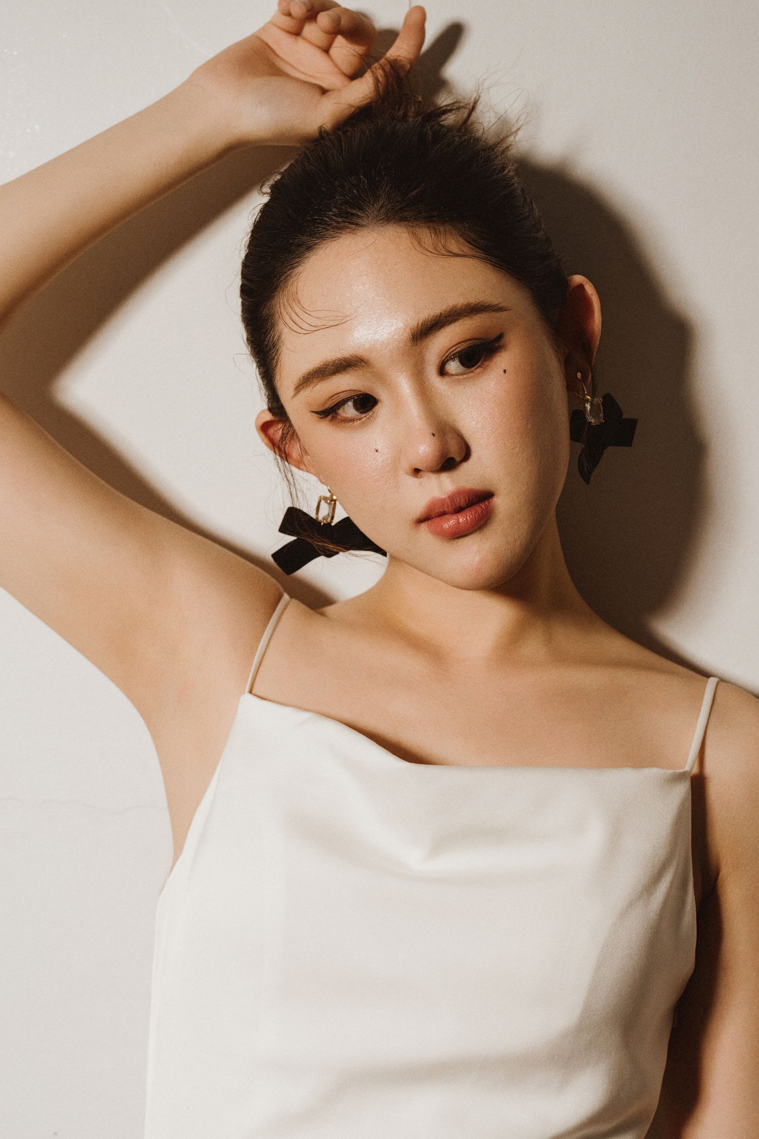 Ethereal beauty portrait with dramatic lighting and white fashion styling.