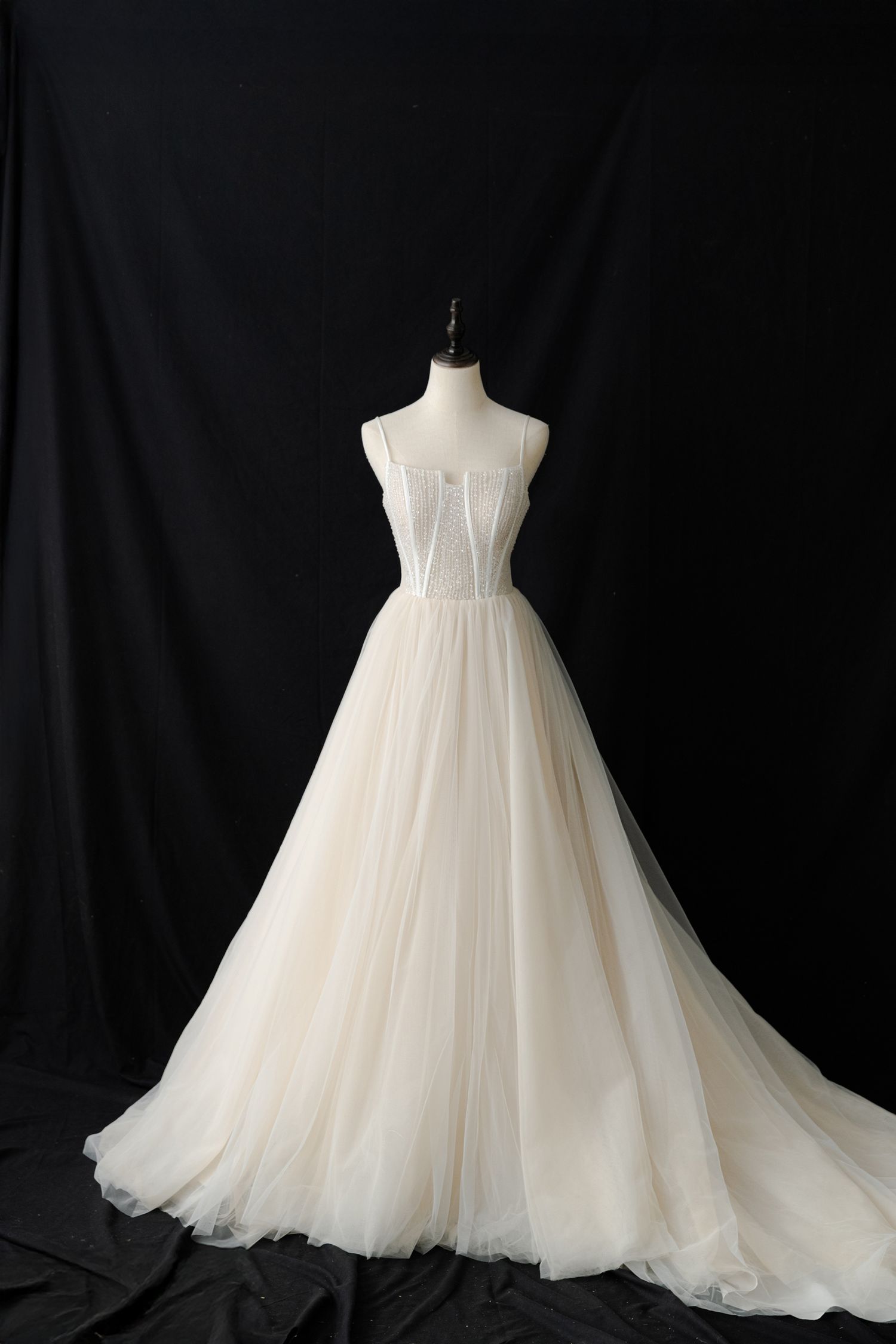 Ethereal ballgown wedding dress with dramatic tulle skirt displayed on dress form.