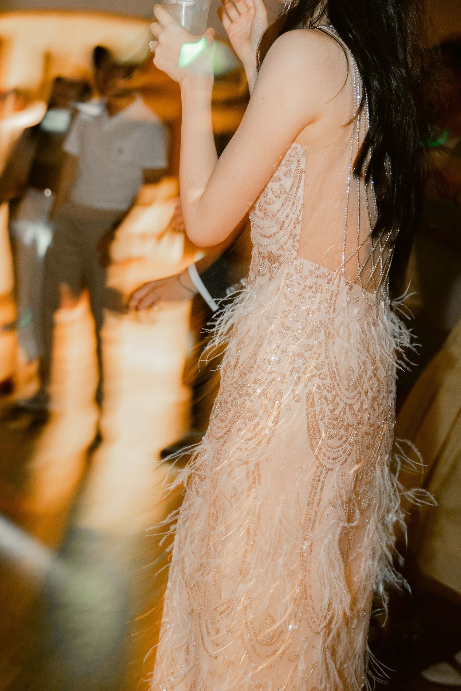 Detail shot of a textured wedding dress with feather embellishments in warm lighting.