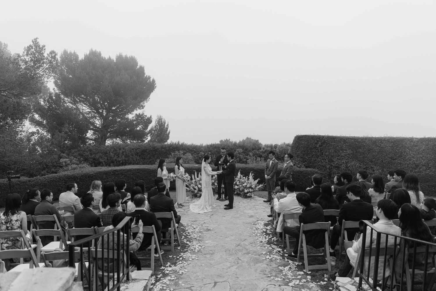 Wedding guests seated in rows of chairs at an outdoor ceremony with mountain views.