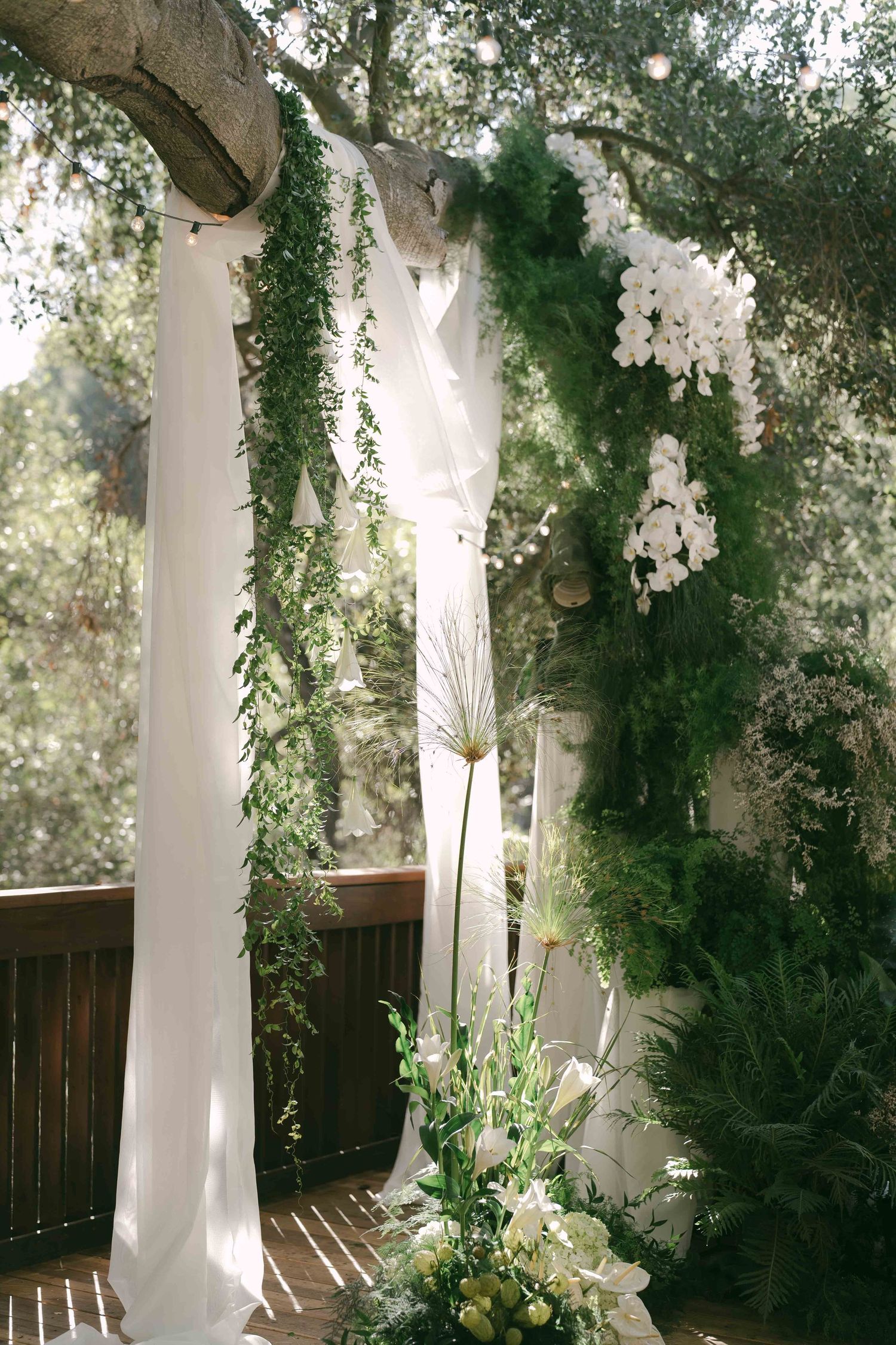 White floral arrangements and greenery decorate outdoor wedding venue columns.