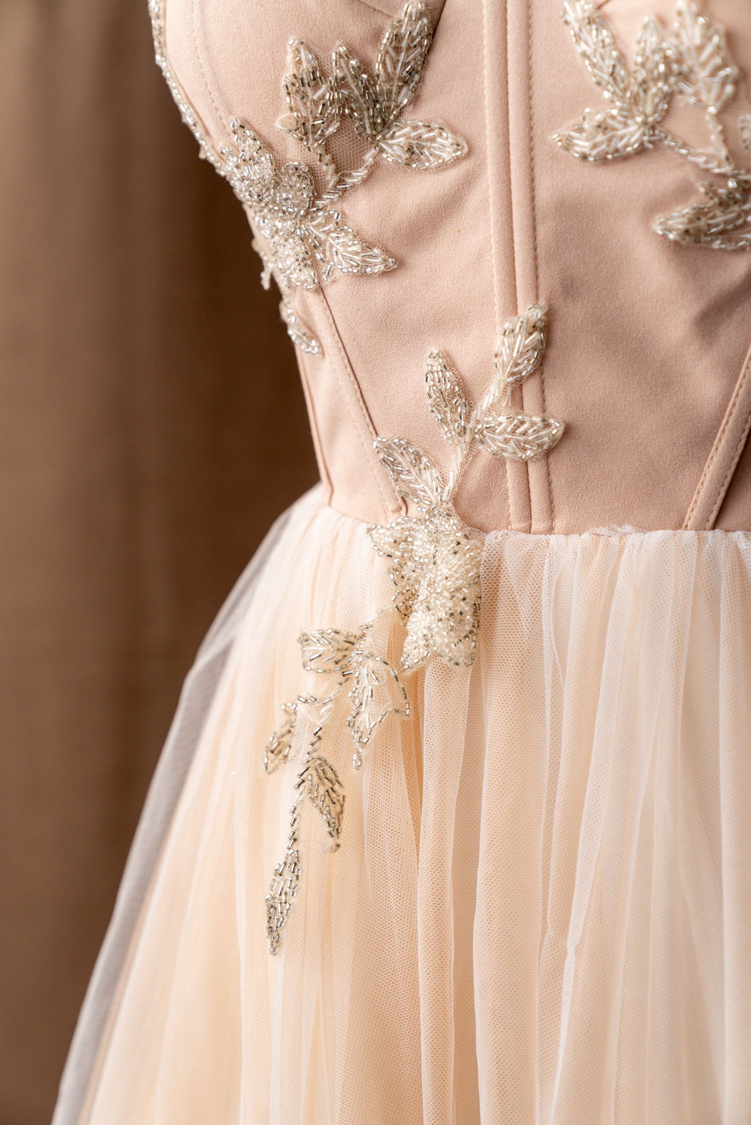 Close-up of beaded floral appliques on a blush pink corset bodice.