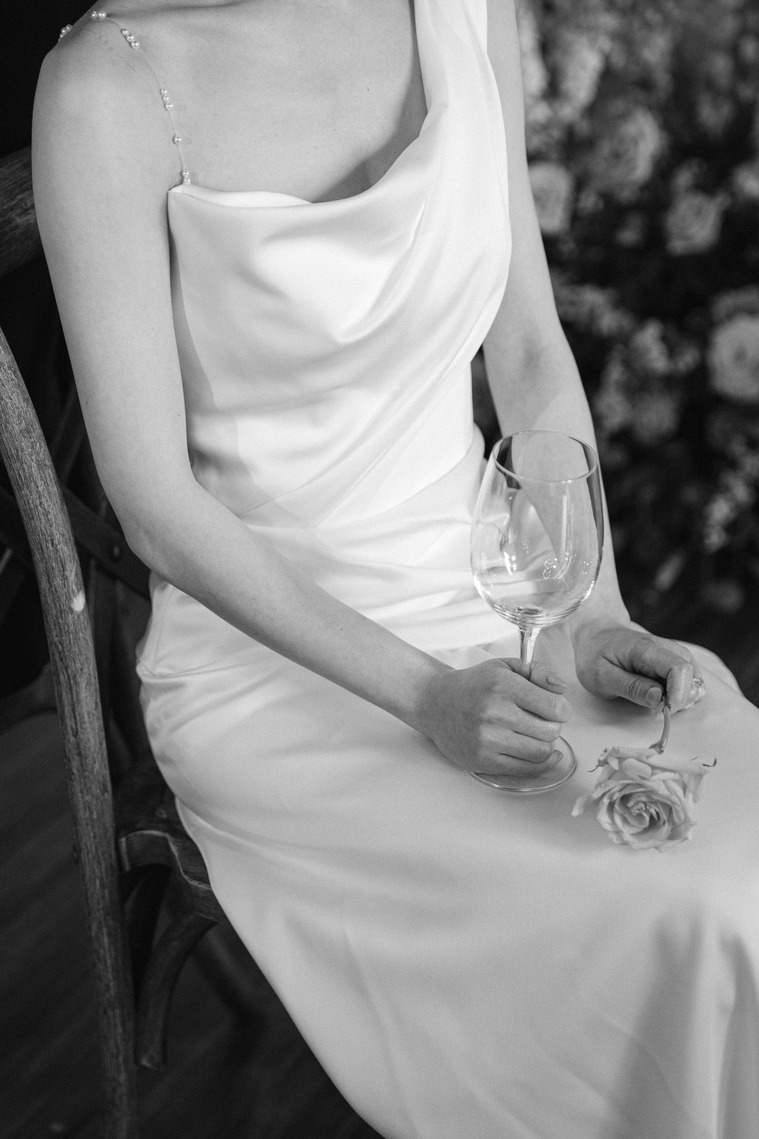 Close-up of hands holding a wine glass while seated in an elegant white dress.