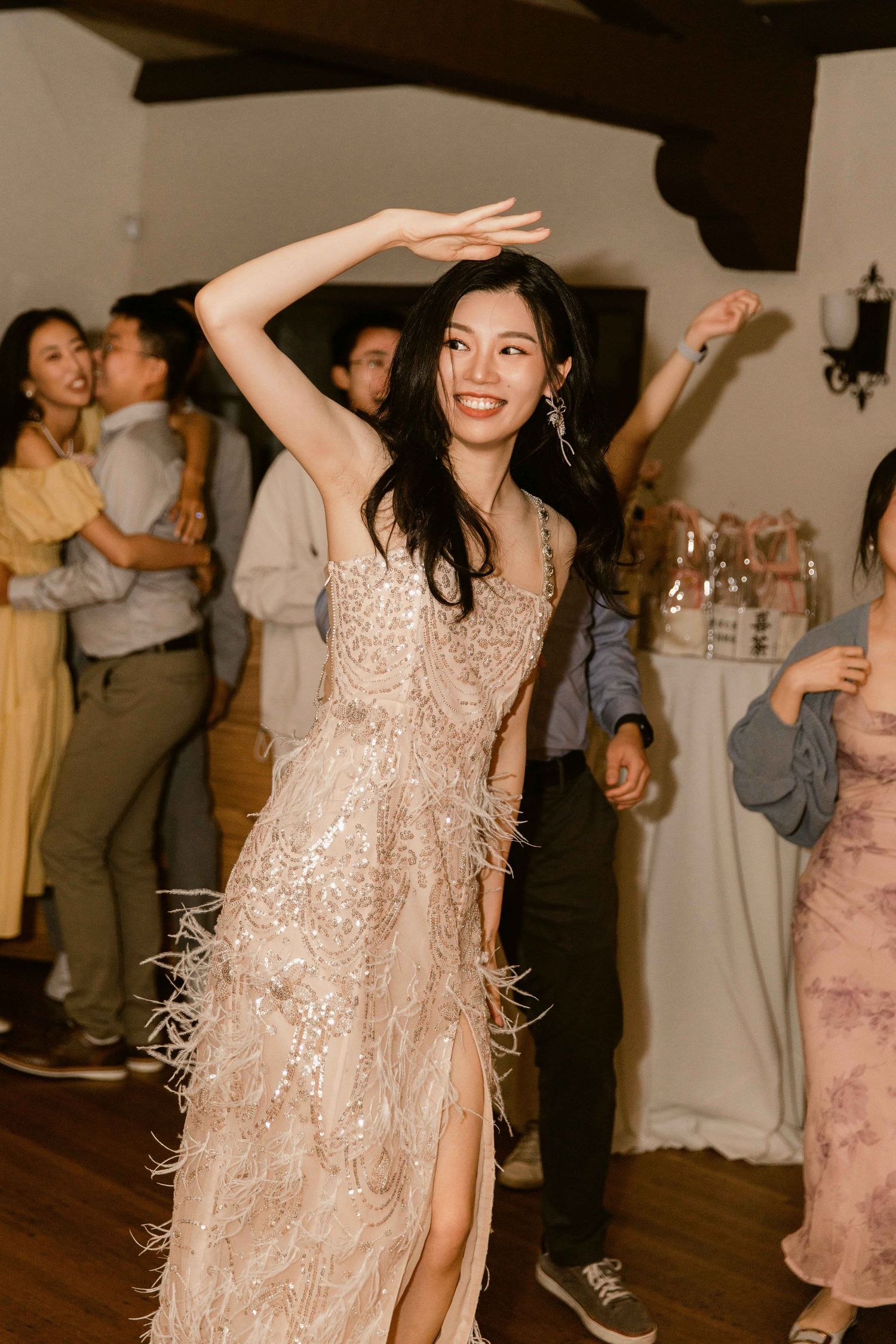 Wedding reception dance party with guests in formal attire under warm lighting.
