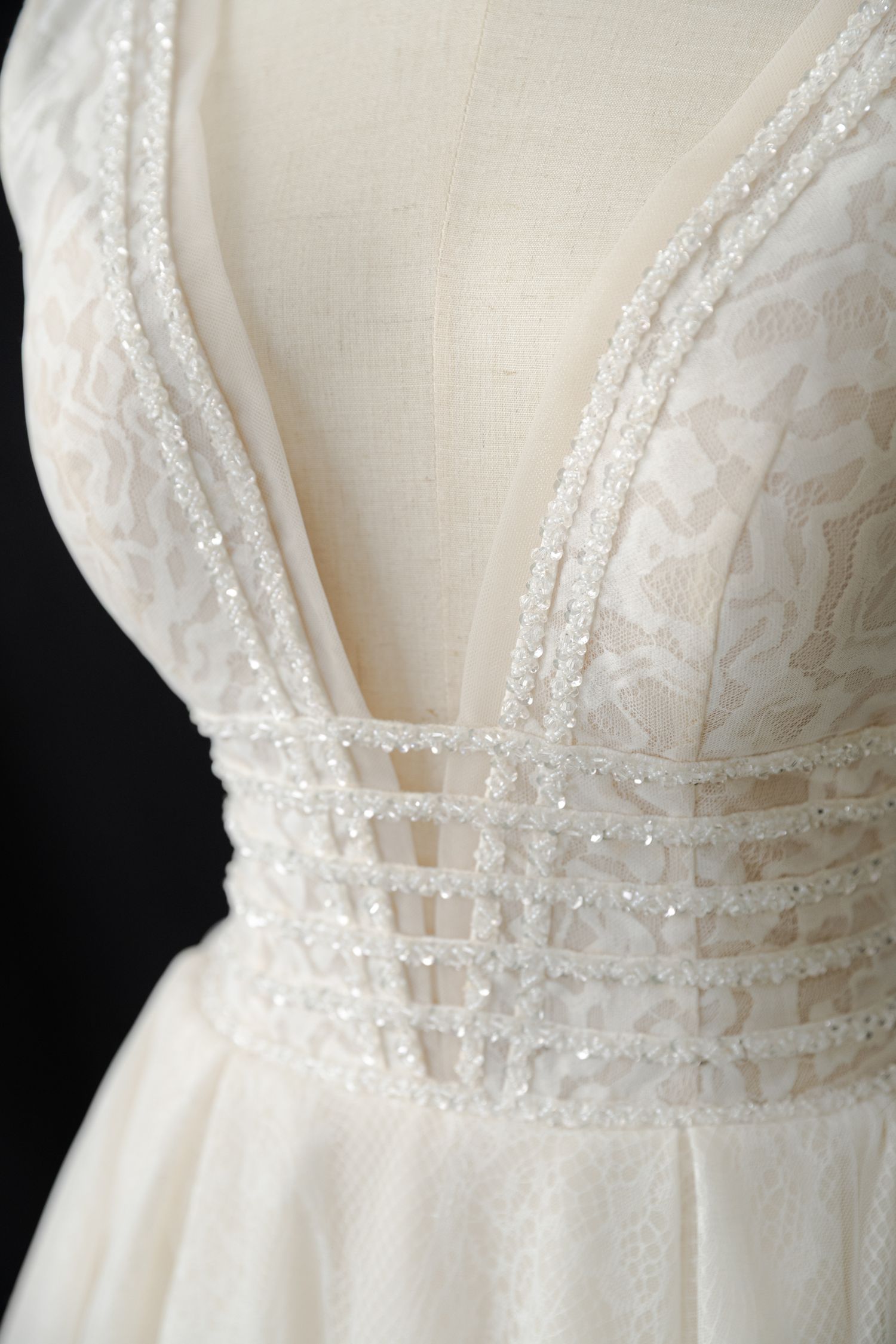 Detailed view of wedding dress bodice showing intricate beading and lace trim.