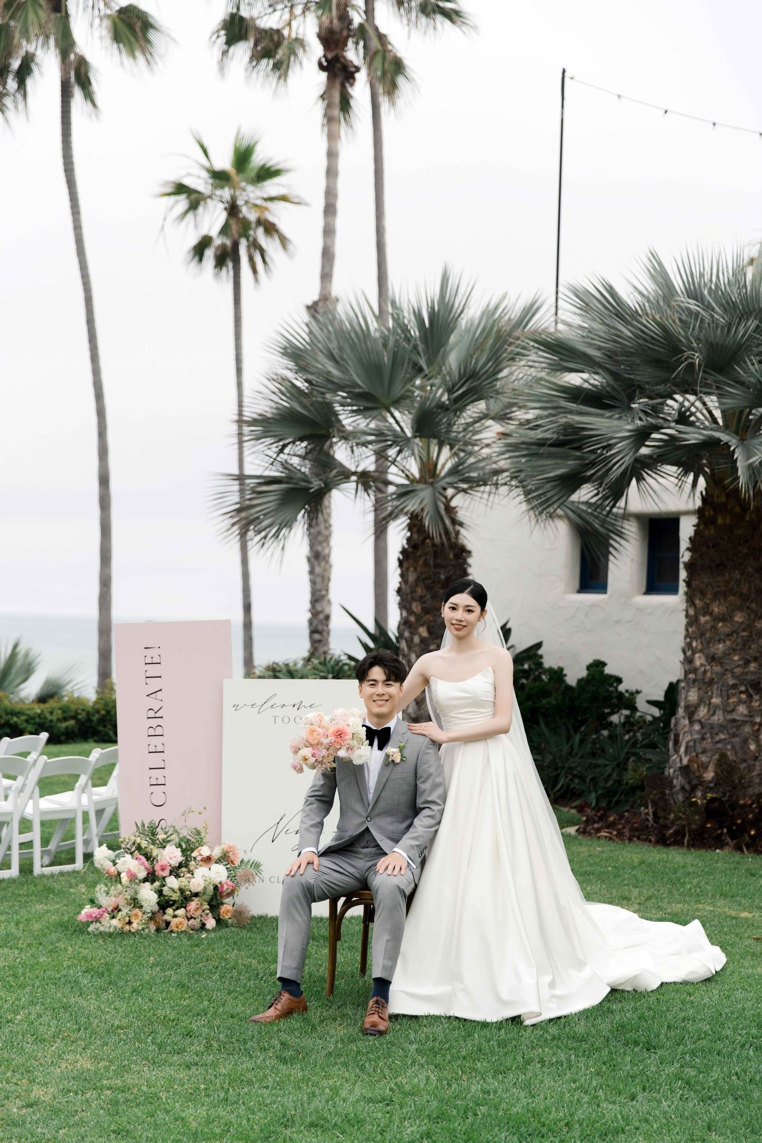 Couple poses for formal wedding portrait with tropical palm trees in background.